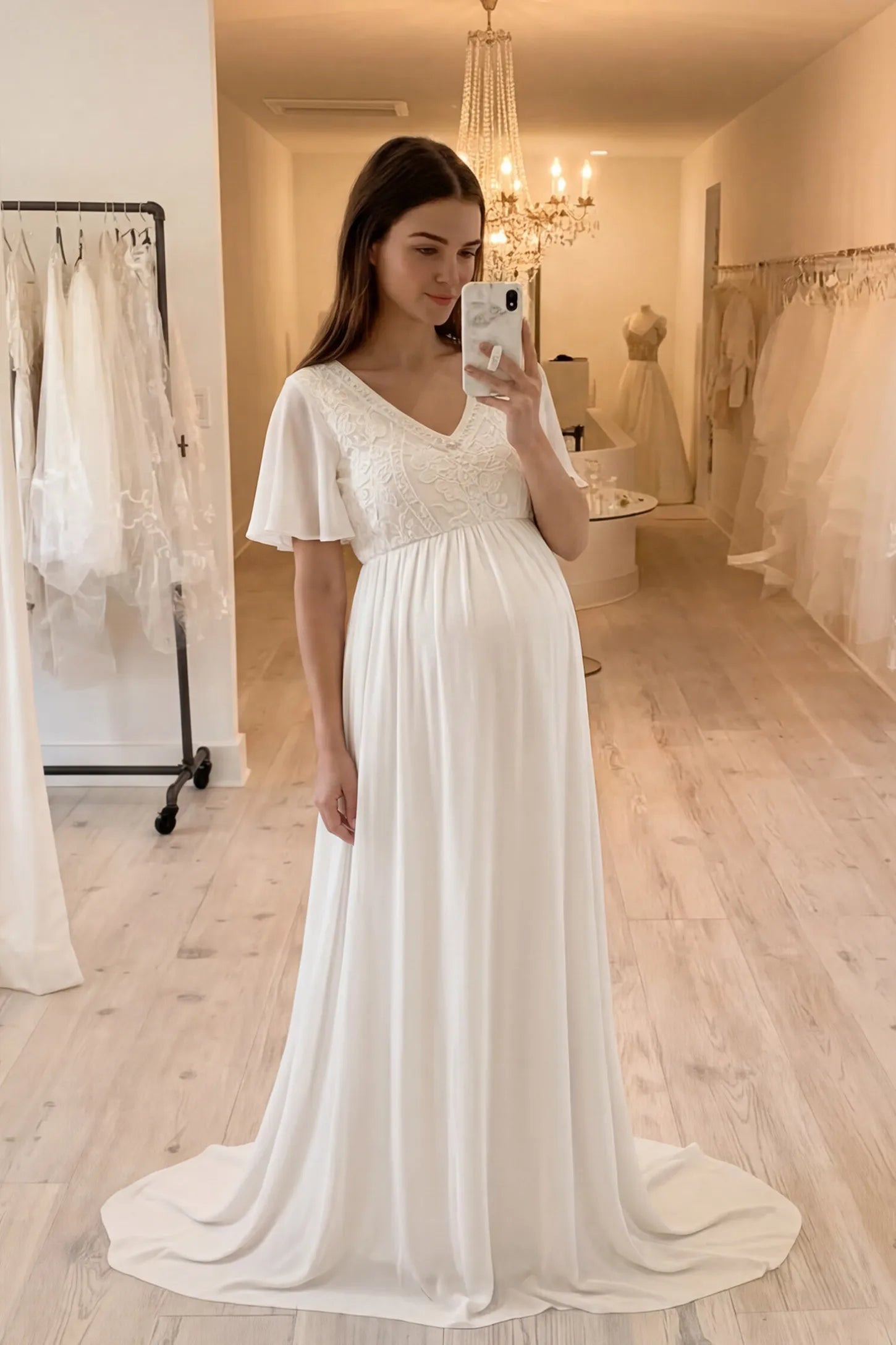 Lace Embroidered Short Flutter Sleeve Maternity Gown Lace embroidered short flutter sleeve maternity gown in white with delicate lace embroidery & flutter sleeves, front view on pregnant model