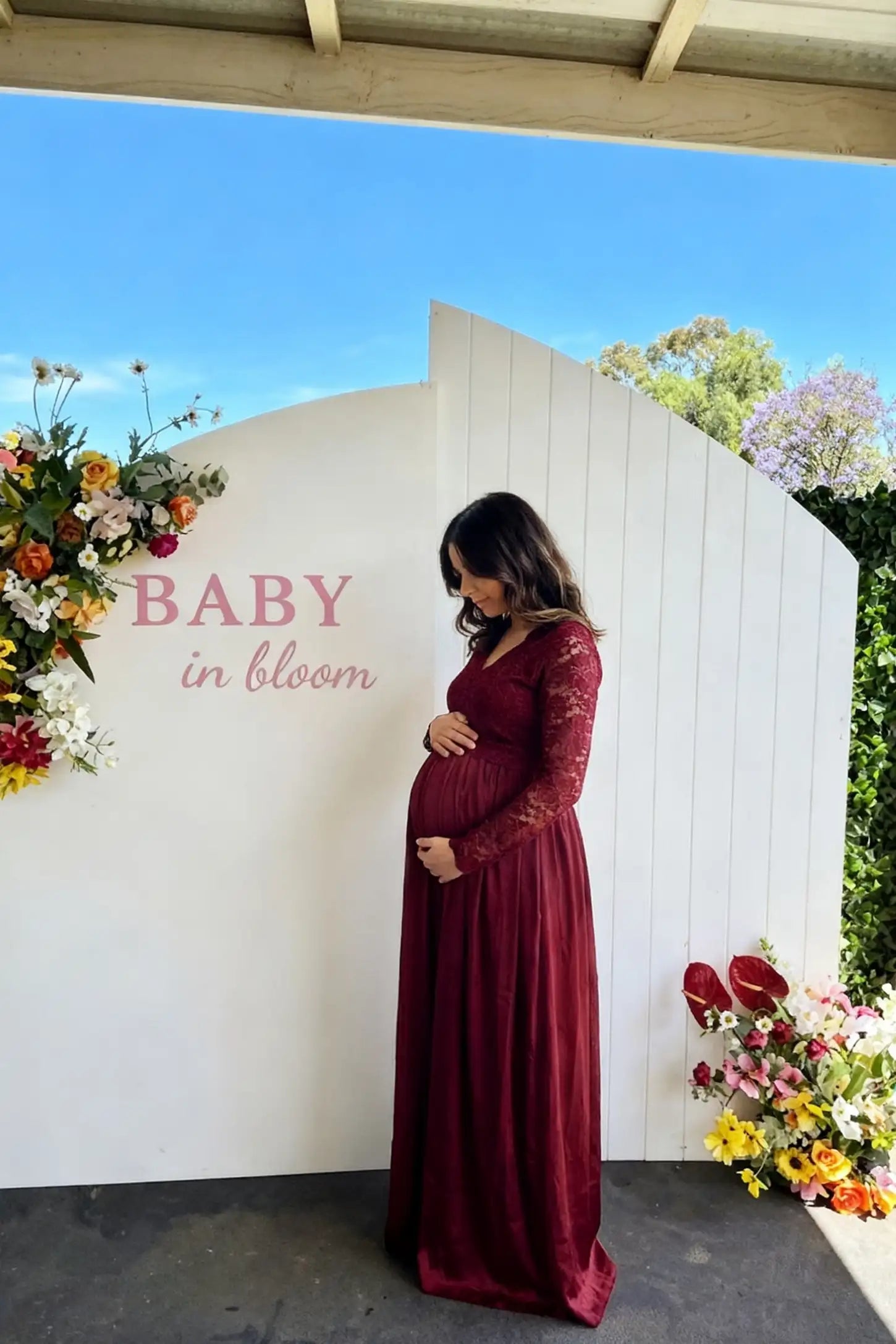 Lace-Spliced Silk Long Sleeve Maxi Maternity Dress Lace-spliced silk long sleeve maxi maternity dress in wine red featuring lace bodice and sleeves in front view on a editorial lifestyle model