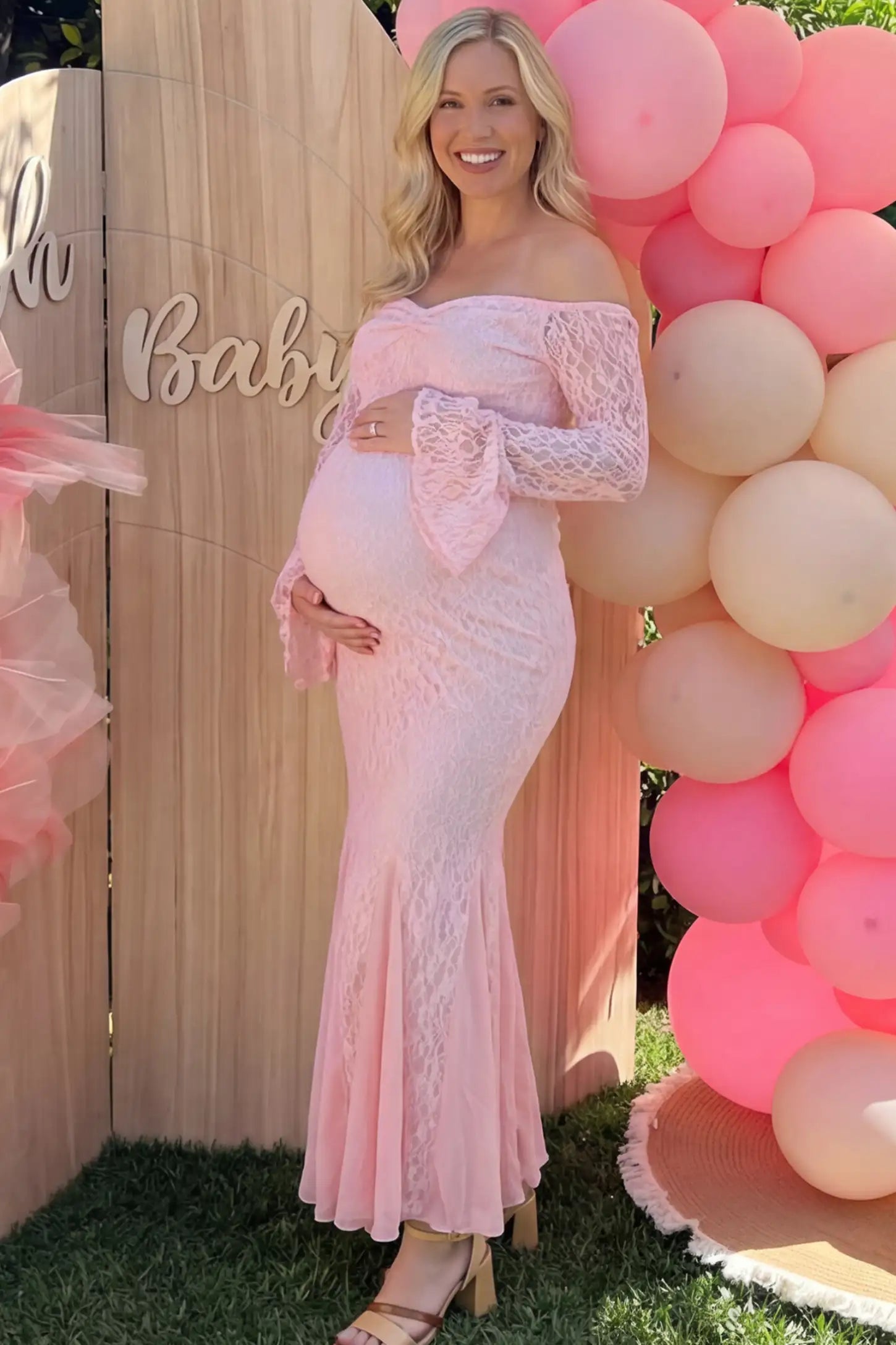 Lace Off Shoulder Mermaid Maternity Gown in pink lace featuring a sweetheart neckline, long sleeves, and a fitted mermaid silhouette on a pregnant woman in outdoor setting front view.
