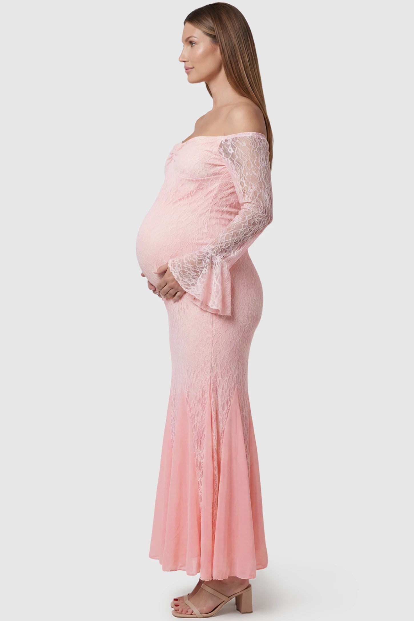 Lace Off Shoulder Mermaid Maternity Gown Lace Off Shoulder Mermaid Maternity Gown in pink lace featuring a sweetheart neckline, long sleeves, and a fitted mermaid silhouette on a pregnant model side view.