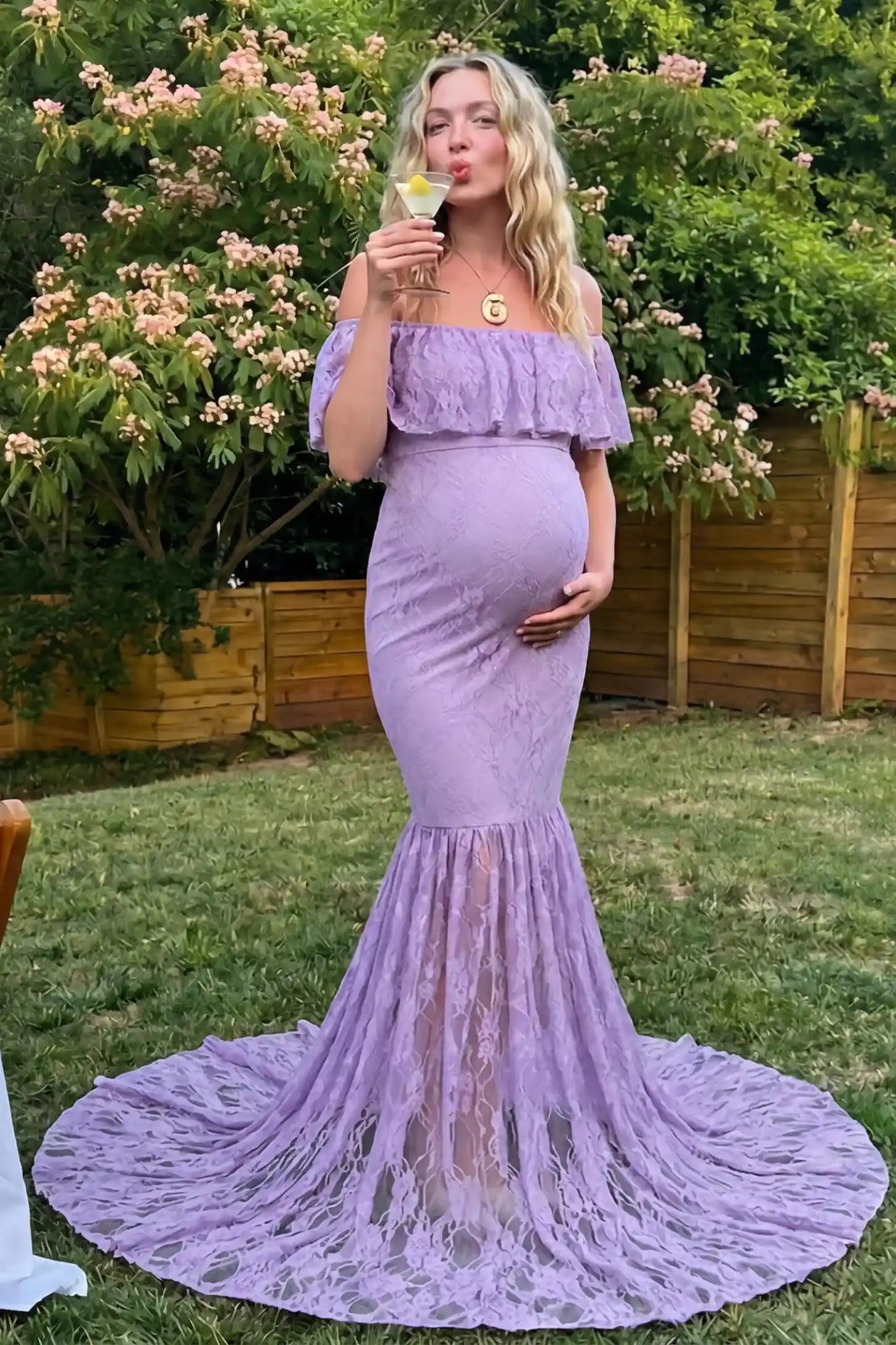 Lace Off-Shoulder Ruffle Short Sleeve Maternity Dress Lace off-shoulder maternity gown in purple featuring ruffle neckline, mermaid silhouette, and extended lace train on pregnant model. 