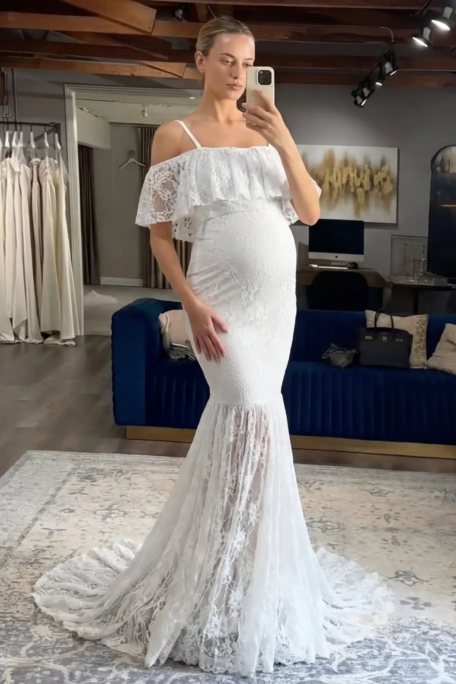 Lace Off-Shoulder Ruffle Short Sleeve Maternity Dress Lace off-shoulder maternity gown in white featuring ruffle neckline, mermaid silhouette, and extended lace train on pregnant model. 