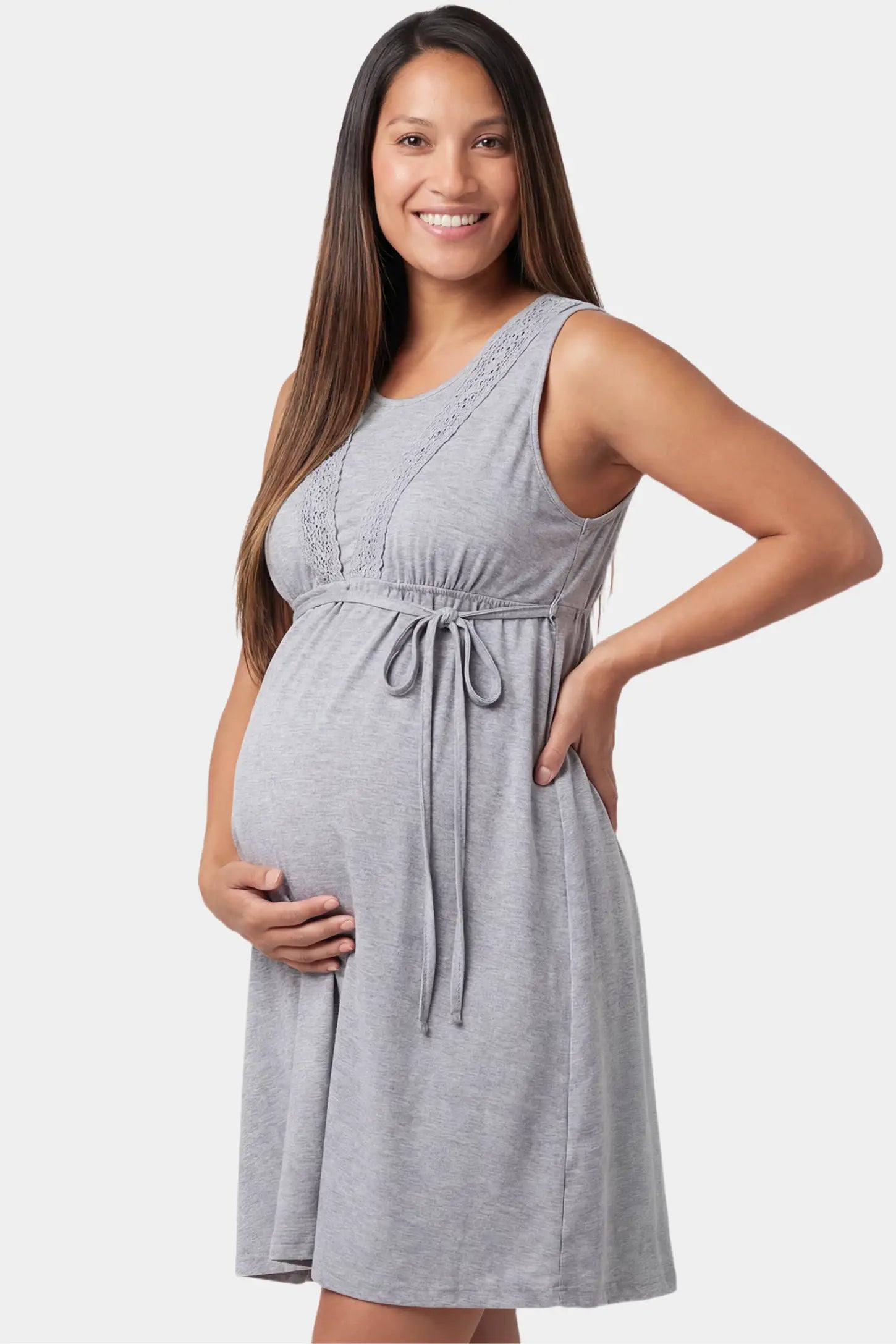 Sleeveless round neck tie-front short maternity and nursing dress in gray featuring breathable stretch fabric in side view on a pregnant model