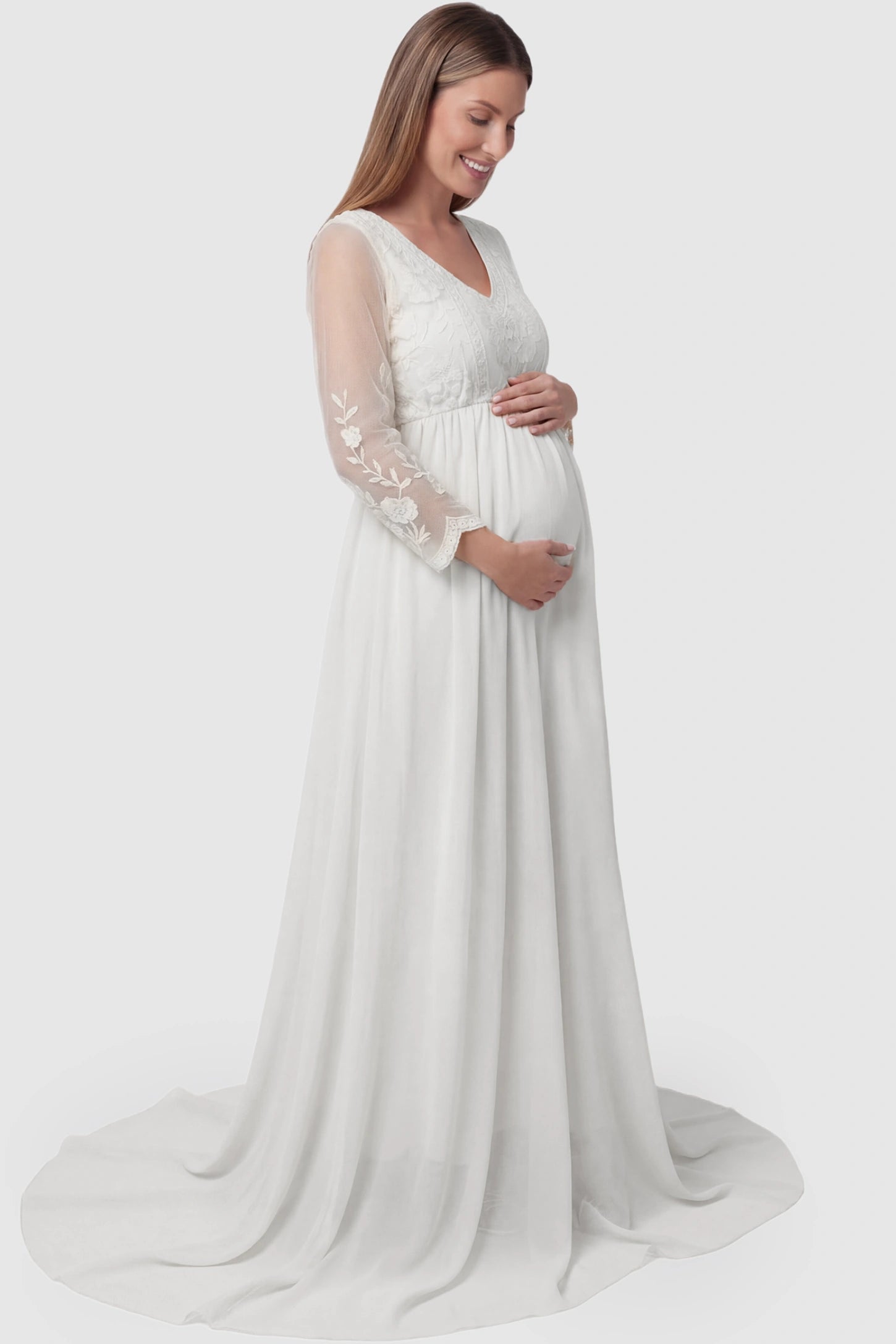 Lace Trim Long Sleeve Train Maternity Gown Lace trim long sleeve train maternity gown in white with flowing train silhouette & mesh sleeves, side view on pregnant model