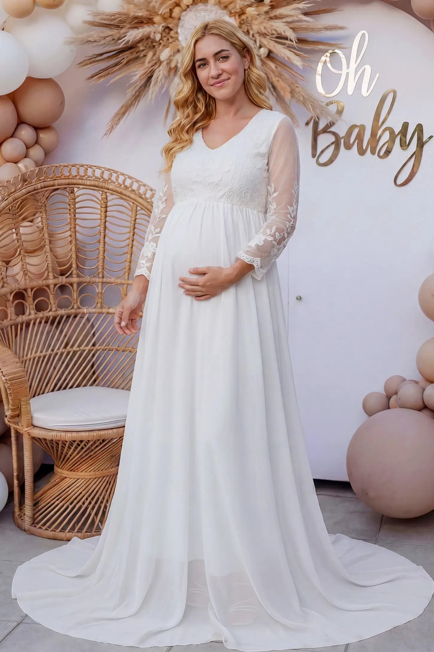 Lace trim long sleeve train maternity gown in white with flowing train silhouette & mesh sleeves, front view on pregnant model