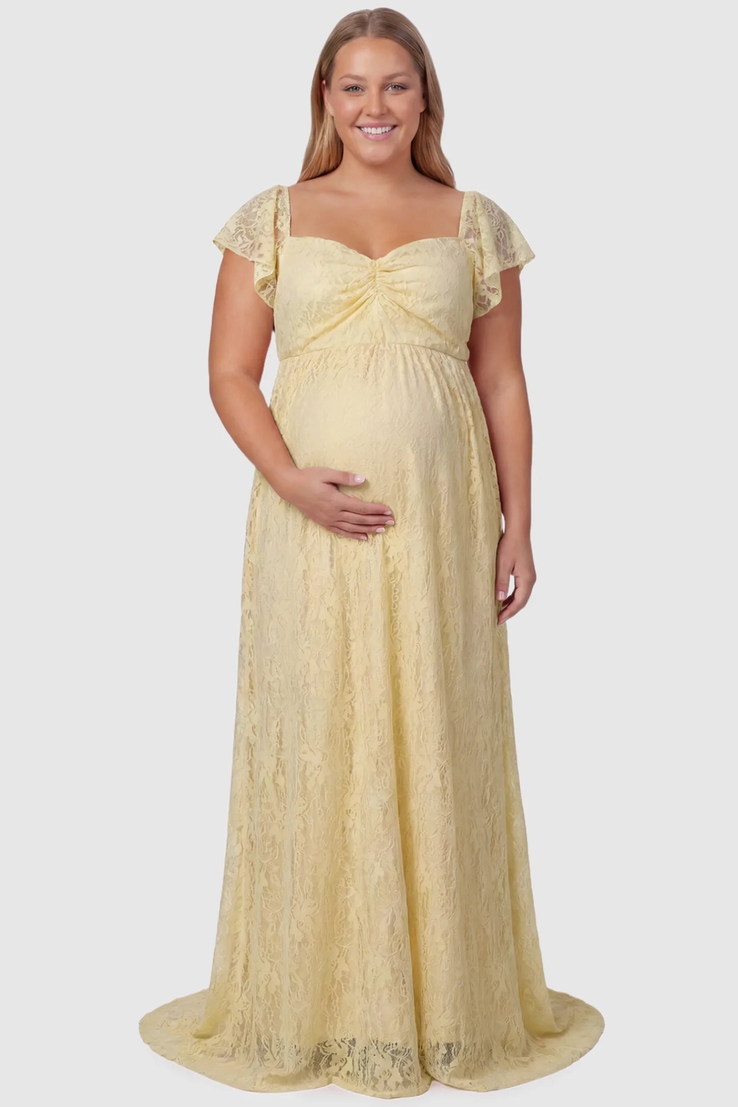 Lace Off Shoulder Maternity Maxi Dress Lace Off Shoulder Maternity Maxi Dress in apricot featuring a sweetheart neckline with a ruched bust and a full-length skirt, shown on a plus size pregnant model, front view.