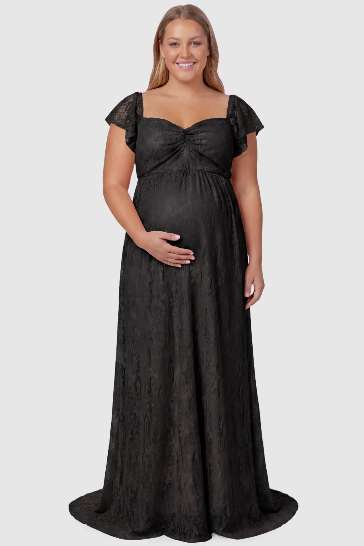 Lace Off Shoulder Maternity Maxi Dress Lace Off Shoulder Maternity Maxi Dress in black featuring a sweetheart neckline with a ruched bust and a full-length skirt, shown on a plus size pregnant model, front view.