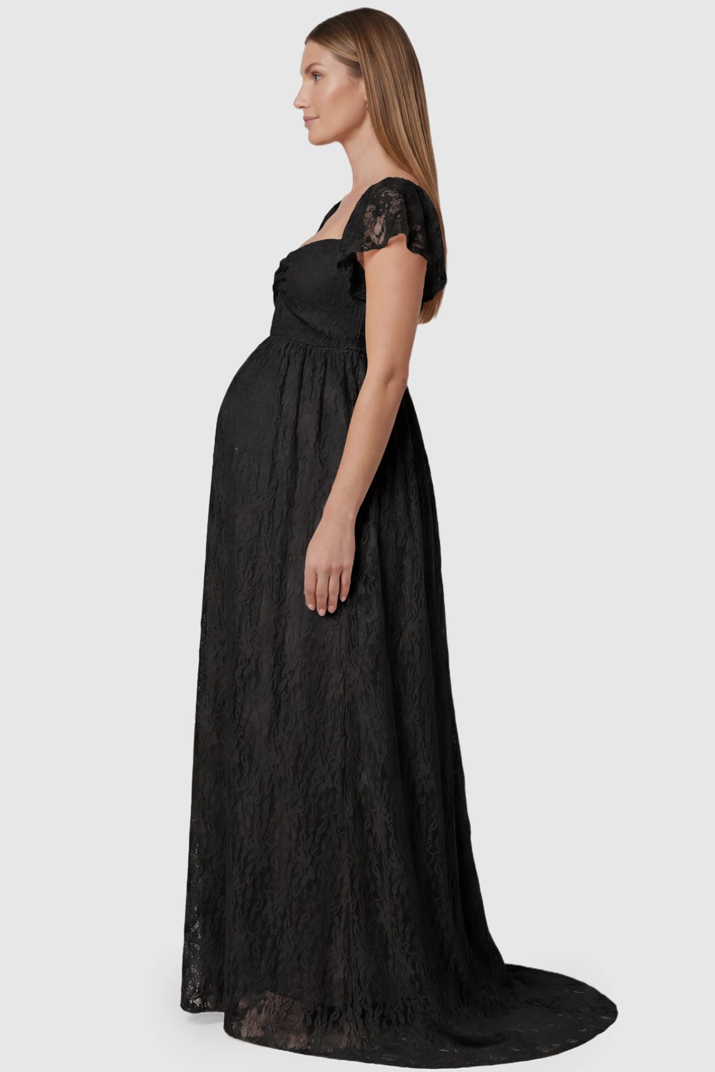 Lace Off Shoulder Maternity Maxi Dress Lace Off Shoulder Maternity Maxi Dress in black featuring a sweetheart neckline with a ruched bust and a full-length skirt, shown on a pregnant model, side view.
