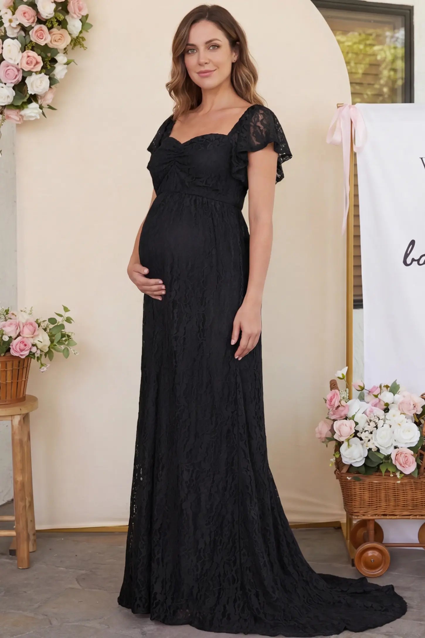 Lace Off Shoulder Maternity Maxi Dress Lace Off Shoulder Maternity Maxi Dress in black featuring a sweetheart neckline with a ruched bust and a full-length skirt, shown on a pregnant woman at a baby shower, front view.