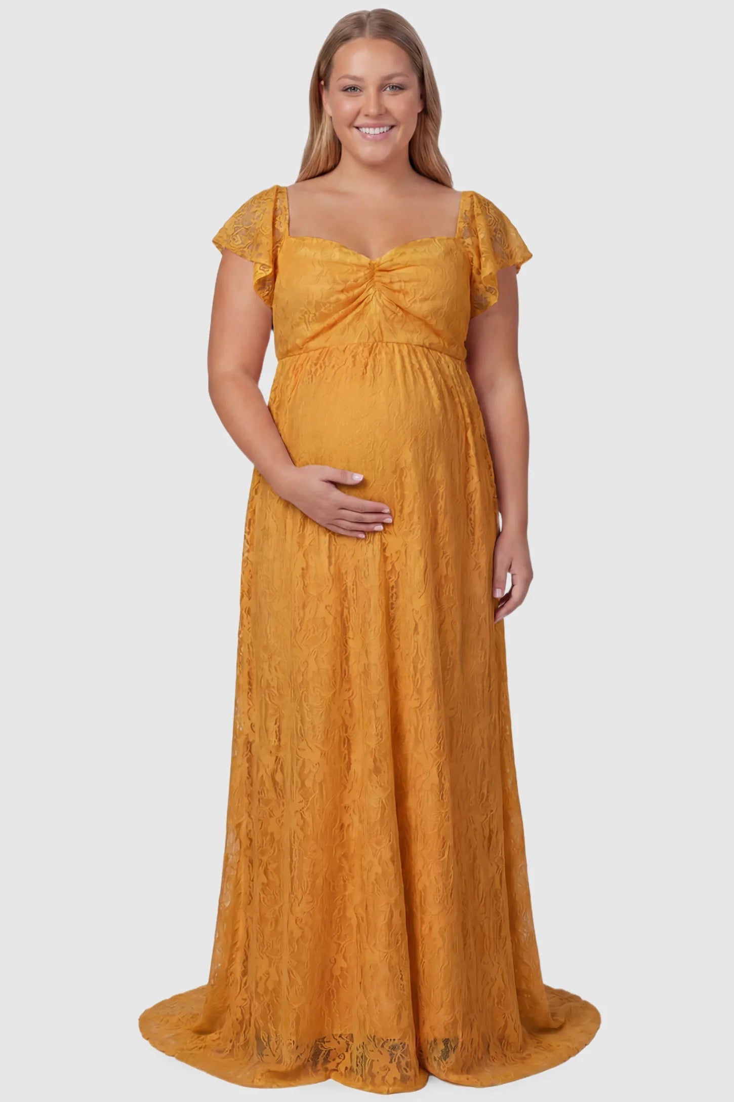 Lace Off Shoulder Maternity Maxi Dress Lace Off Shoulder Maternity Maxi Dress in gold featuring a sweetheart neckline with a ruched bust and a full-length skirt, shown on a plus size pregnant model, front view.