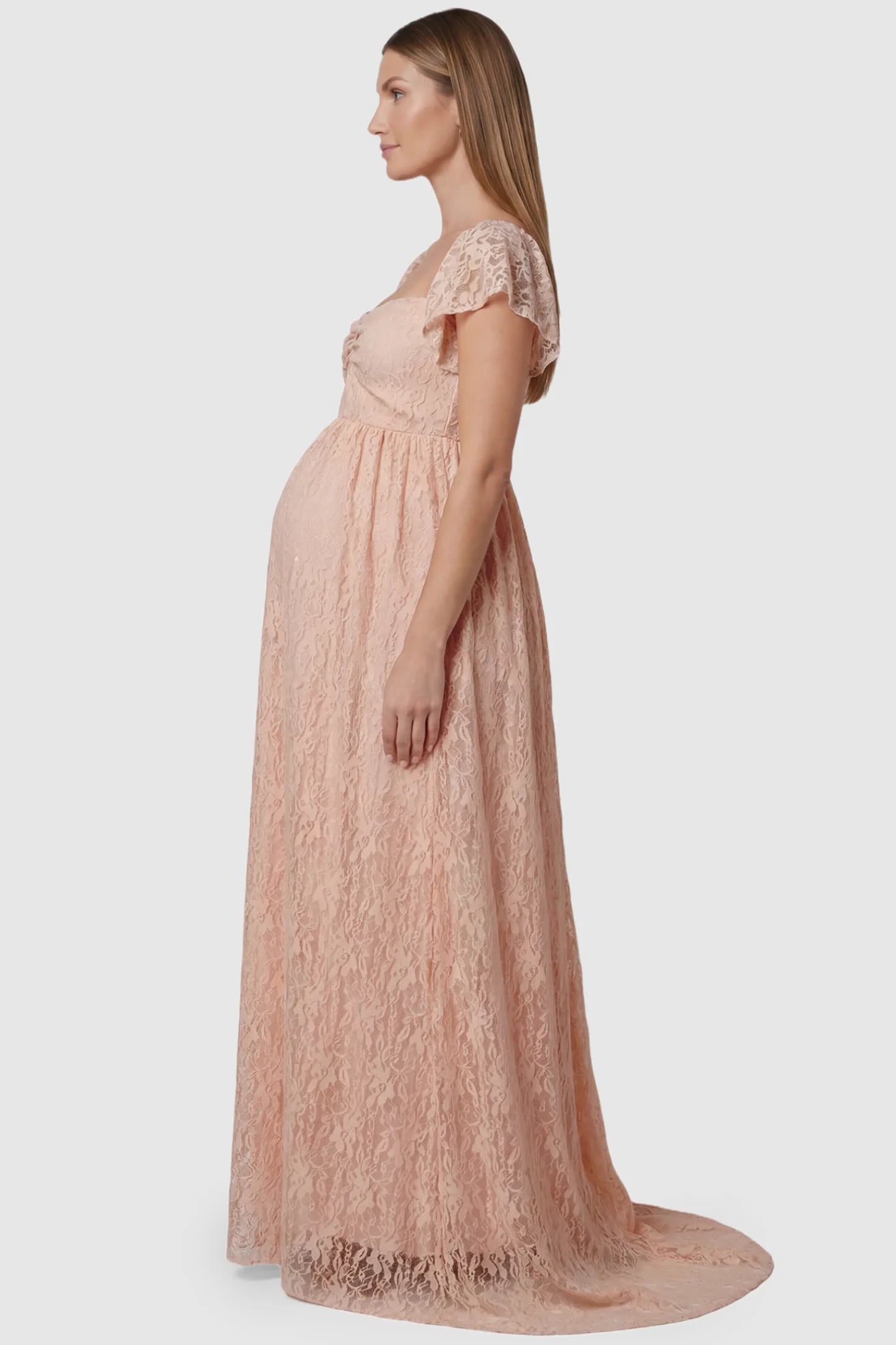 Lace Off Shoulder Maternity Maxi Dress Lace Off Shoulder Maternity Maxi Dress in pink featuring a sweetheart neckline with a ruched bust and a full-length skirt, shown on a pregnant model, side view.