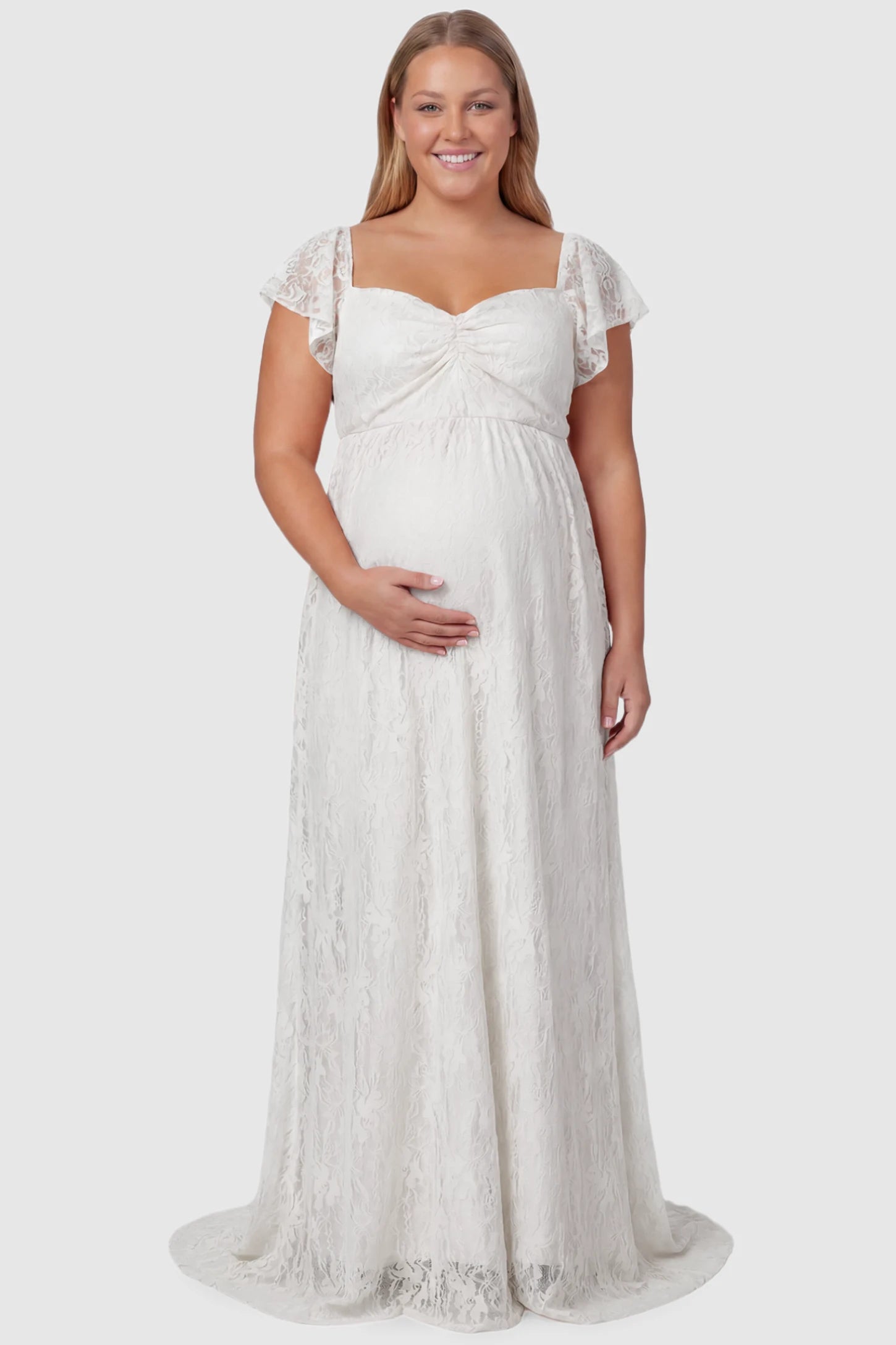 Lace Off Shoulder Maternity Maxi Dress Lace Off Shoulder Maternity Maxi Dress in white featuring a sweetheart neckline with a ruched bust and a full-length skirt, shown on a plus size pregnant model, front view.