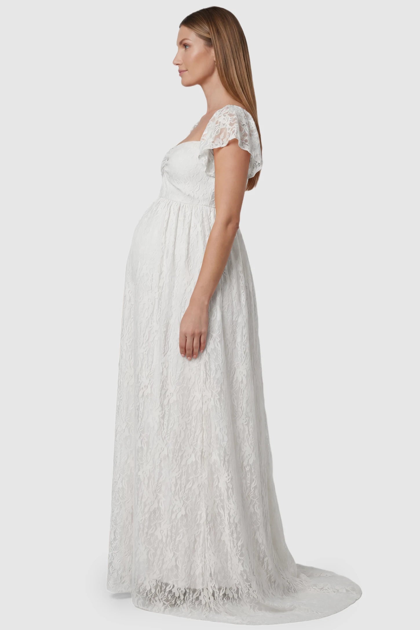 Lace Off Shoulder Maternity Maxi Dress Lace Off Shoulder Maternity Maxi Dress in white featuring a sweetheart neckline with a ruched bust and a full-length skirt, shown on a pregnant model, side view.