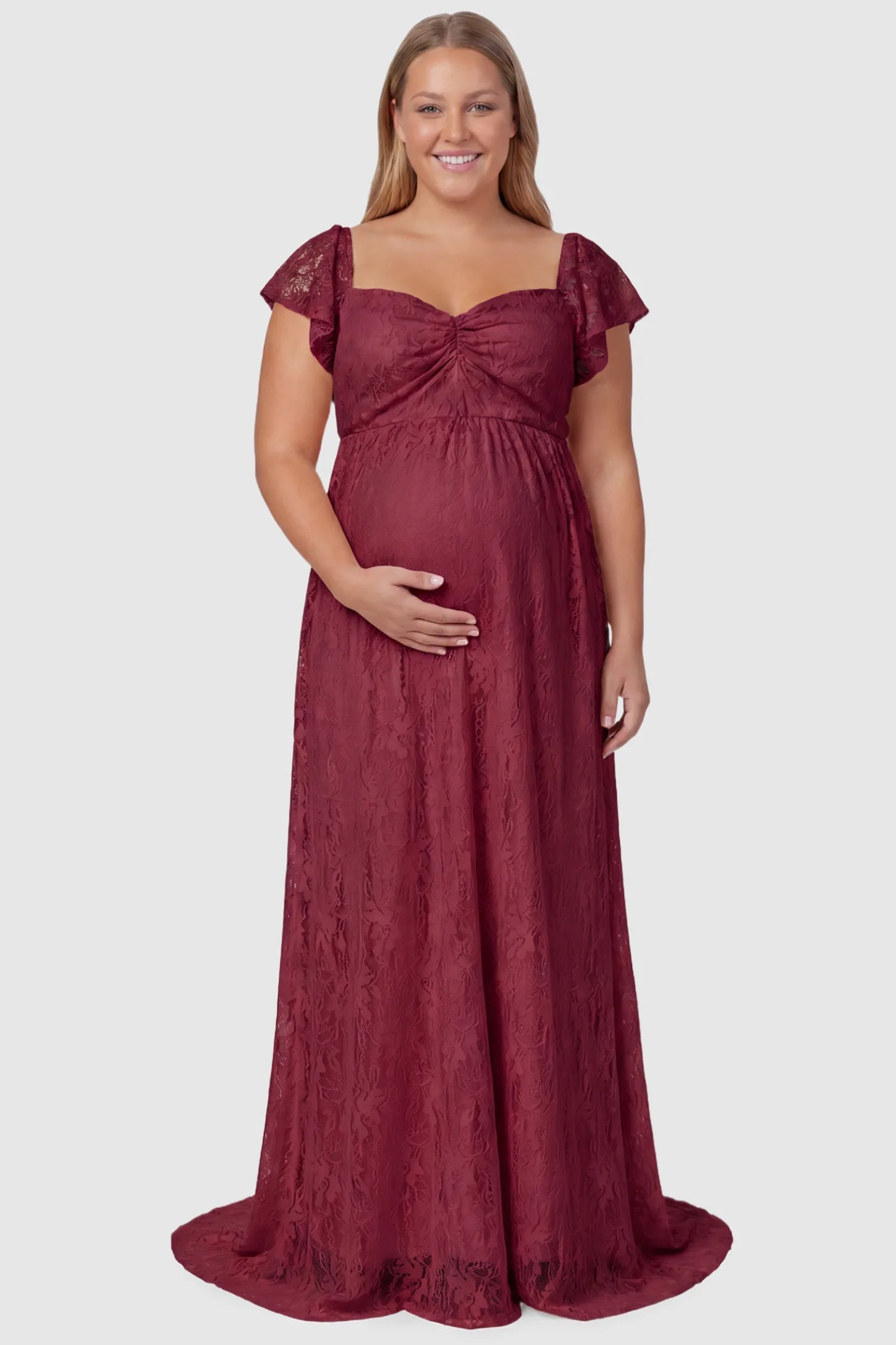 Lace Off Shoulder Maternity Maxi Dress Lace Off Shoulder Maternity Maxi Dress in wine red featuring a sweetheart neckline with a ruched bust and a full-length skirt, shown on a plus size pregnant model, front view.