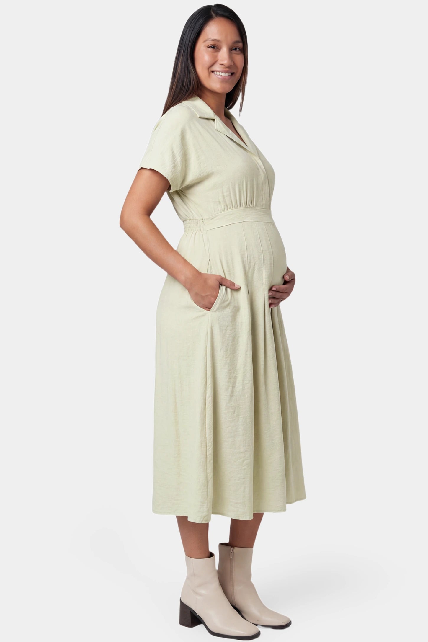 Lapel collar short sleeve A-line midi maternity dress in light green featuring a side pocket in full body side view on a pregnant model