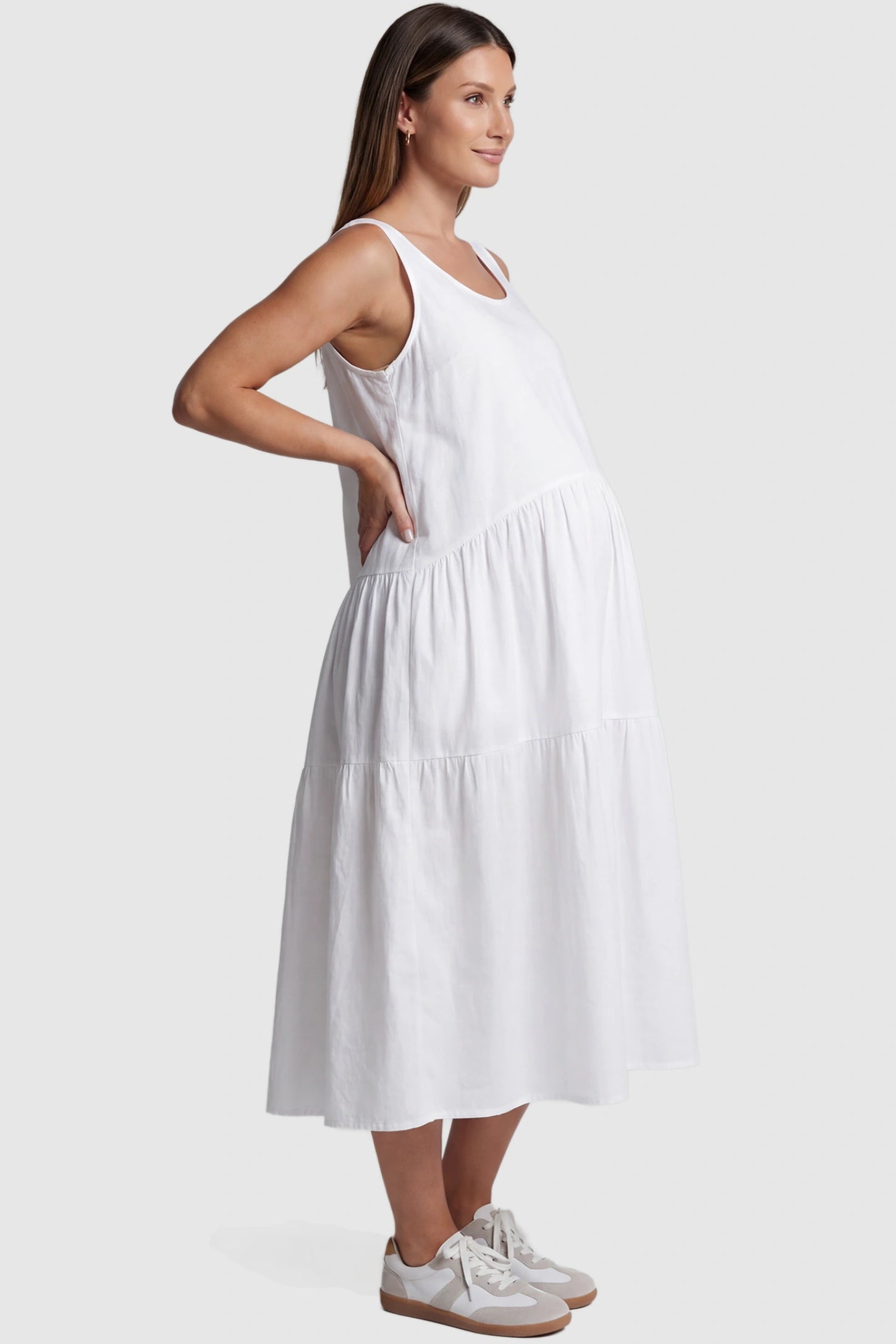 Layered Skirt A-Line Maternity Midi Dress Layered skirt A-line maternity midi dress in white with sleeveless design, side view on pregnant model