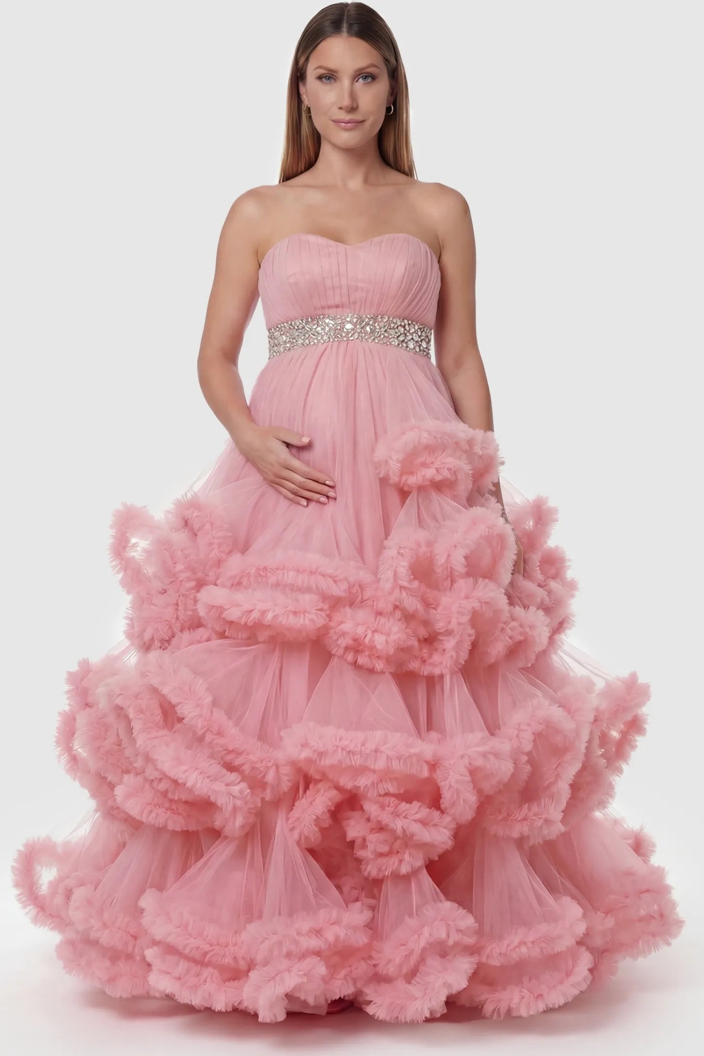 Multi-Layered Pleated Tulle Strapless Bodice Maxi Maternity Gown Multi-layered pleated tulle strapless bodice maxi maternity gown in pink featuring structured strapless bodice in front view on a pregnant model