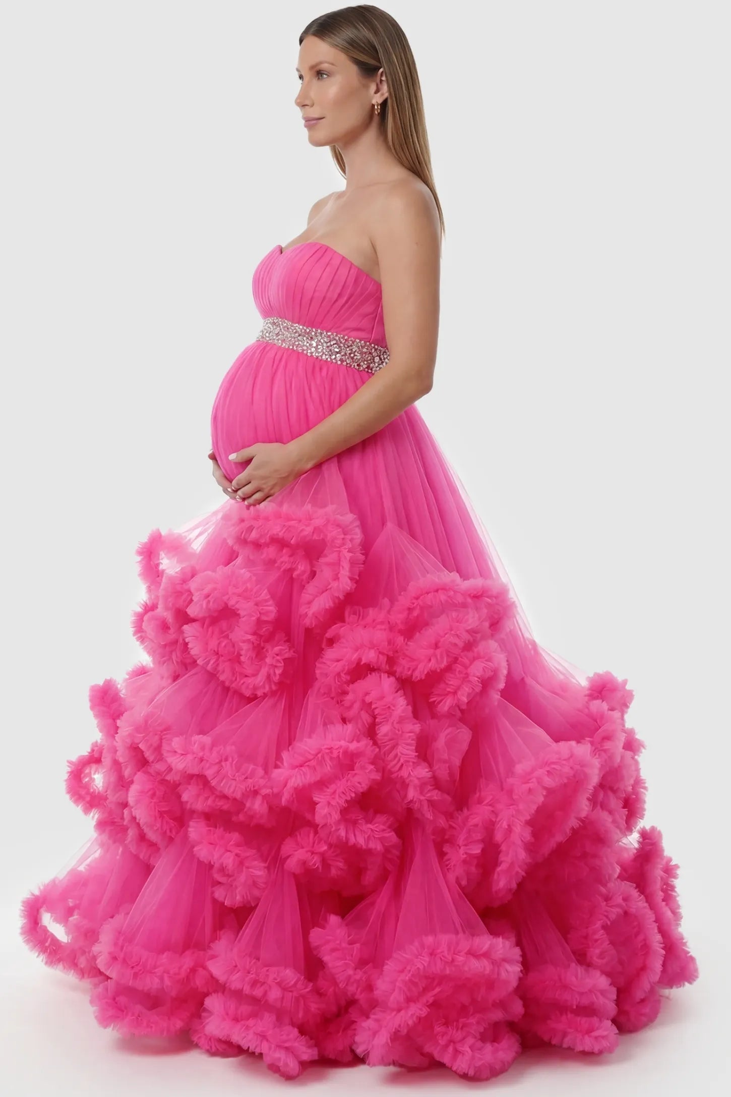 Multi-layered pleated tulle strapless bodice maxi maternity gown in rose red featuring layered pleated tulle skirt in side view on a pregnant model