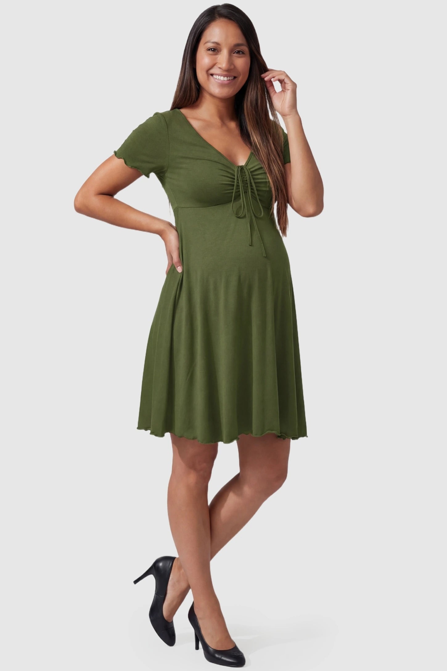 Lettuce Trim A-Line Mini Maternity Dress Lettuce Trim A-Line Mini Maternity Dress in Green featuring a knot front drawstring on a pregnant model.