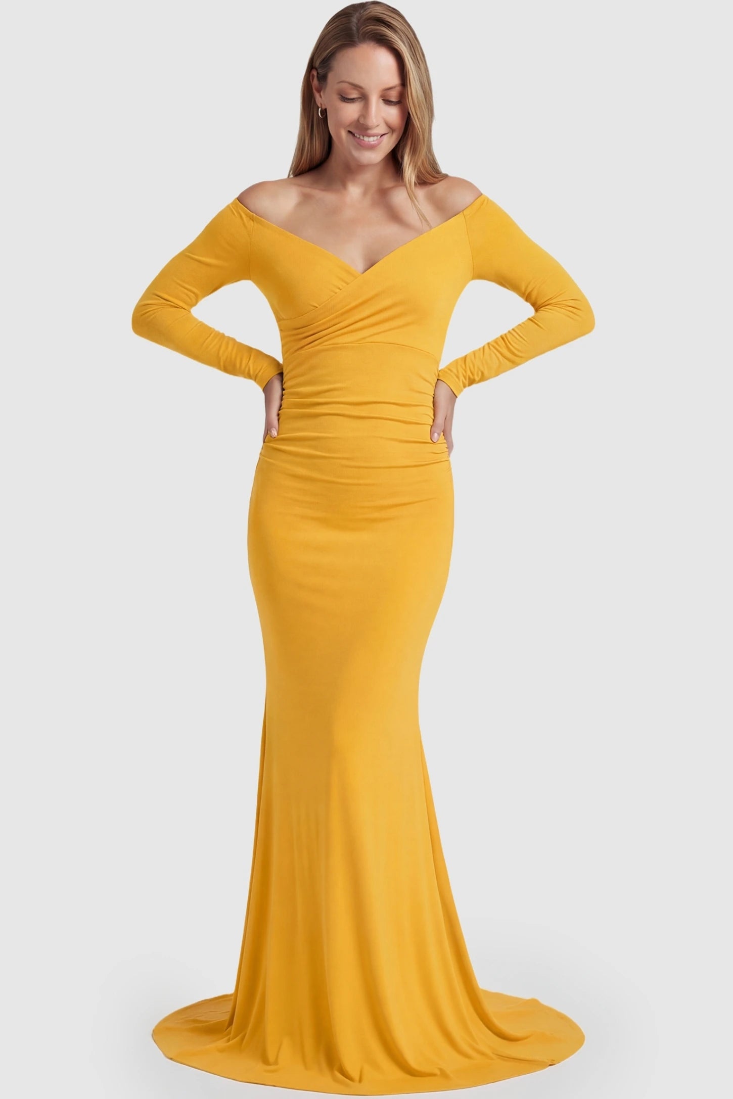 Off-Shoulder Long Sleeve Trailing Maxi Maternity Dress Off-shoulder long sleeve trailing maxi maternity dress in mustard yellow featuring dramatic full train and elegant long sleeves in full body view on a postpartum model