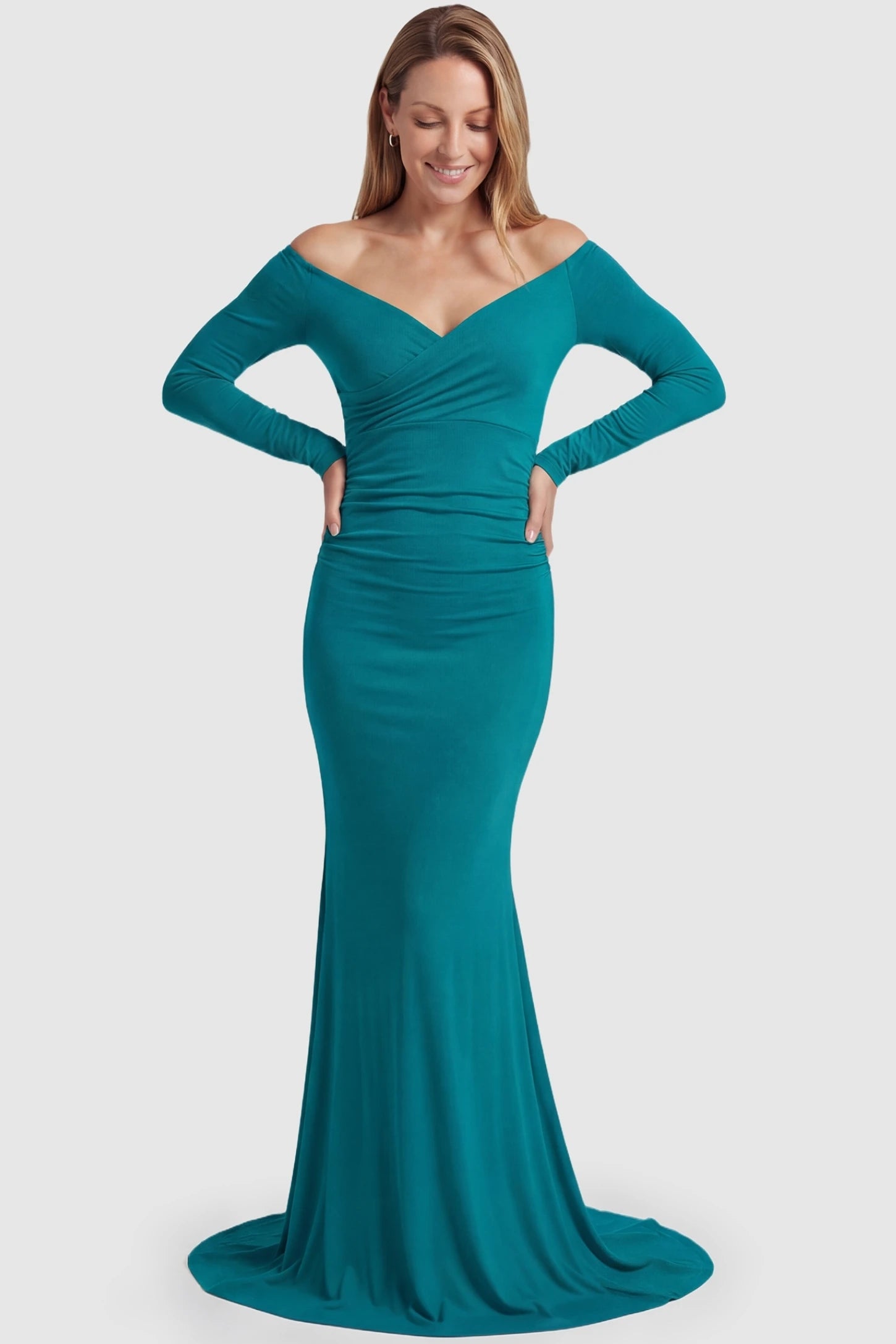Off-Shoulder Long Sleeve Trailing Maxi Maternity Dress Off-shoulder long sleeve trailing maxi maternity dress in turquoise featuring dramatic full train and elegant long sleeves in full body view on a postpartum model