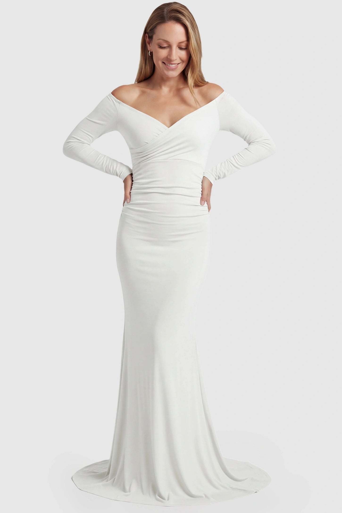 Off-Shoulder Long Sleeve Trailing Maxi Maternity Dress Off-shoulder long sleeve trailing maxi maternity dress in white featuring dramatic full train and elegant long sleeves in full body view on a postpartum model
