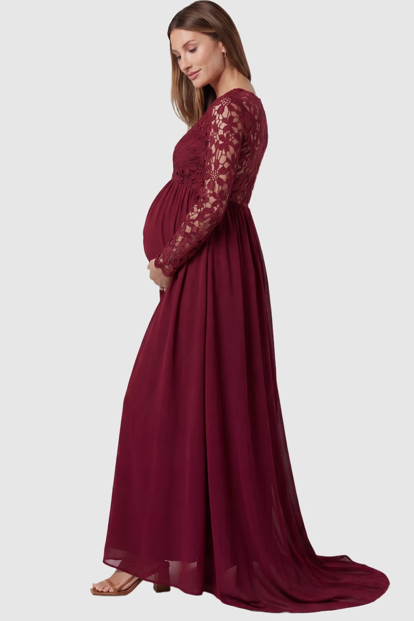 Lace Long Sleeve Full Skirt Maxi Maternity Dress Lace long sleeve full skirt maxi maternity dress in burgundy with elegant long sleeves & lace bodice, side view on pregnant model
