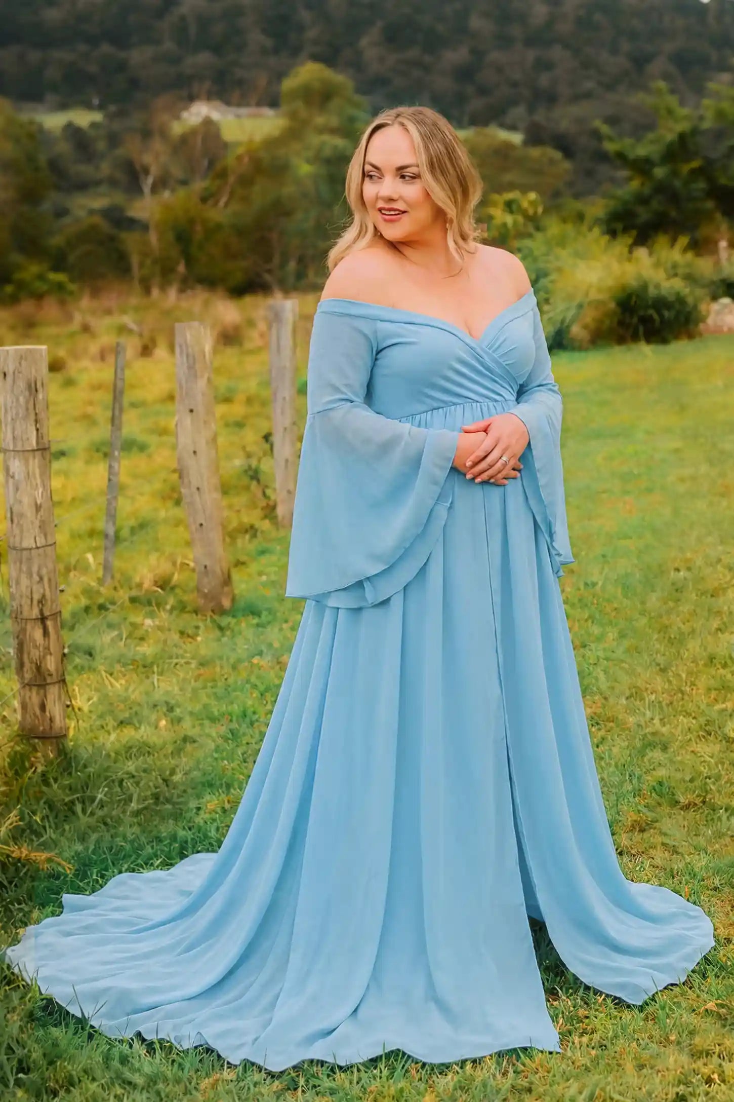 Off-the-Shoulder Long Train Maxi Maternity Dress Off-the-shoulder long train maxi maternity dress in light blue featuring off-shoulder and long-train in full body front view on a editorial lifestyle model