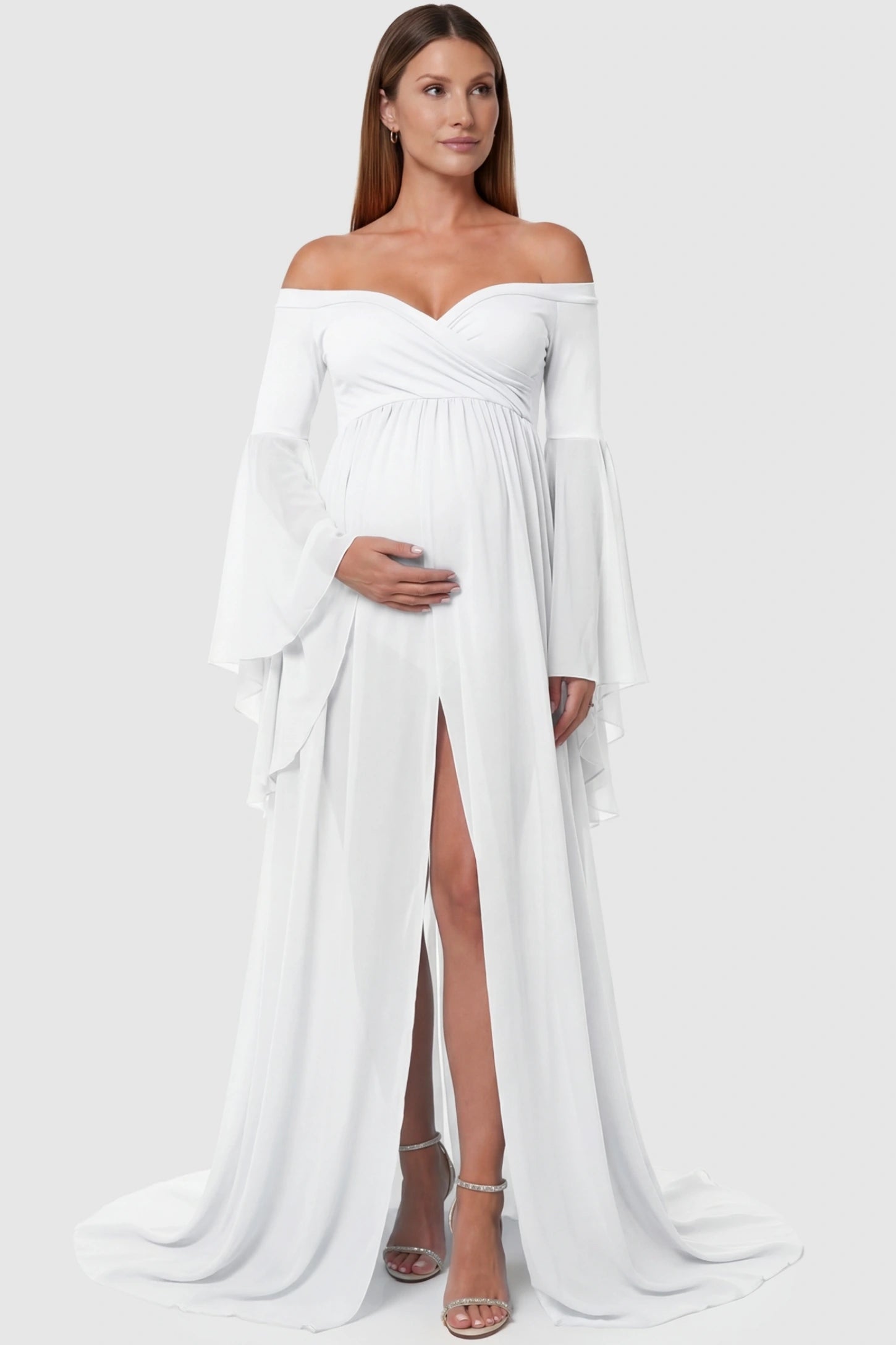 Off-the-shoulder long train maxi maternity dress in white featuring a high front-slit in full body front view on a pregnant model