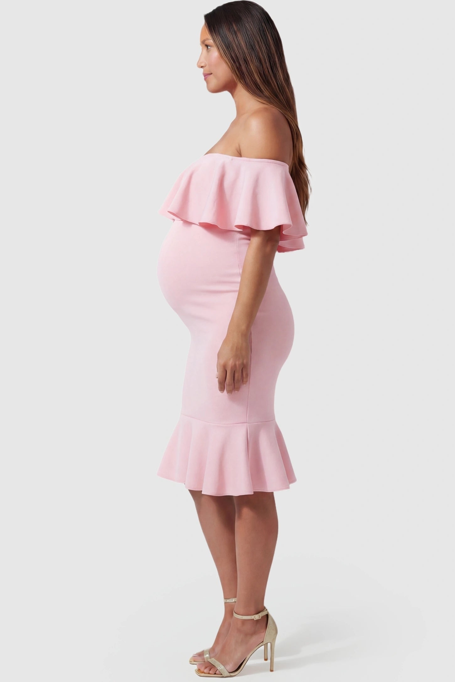 Ruffled Off-Shoulder Mermaid Hem Midi Maternity Dress Ruffled off-shoulder mermaid hem midi maternity dress in pink featuring curve-enhancing mermaid hem in side view on a pregnant model