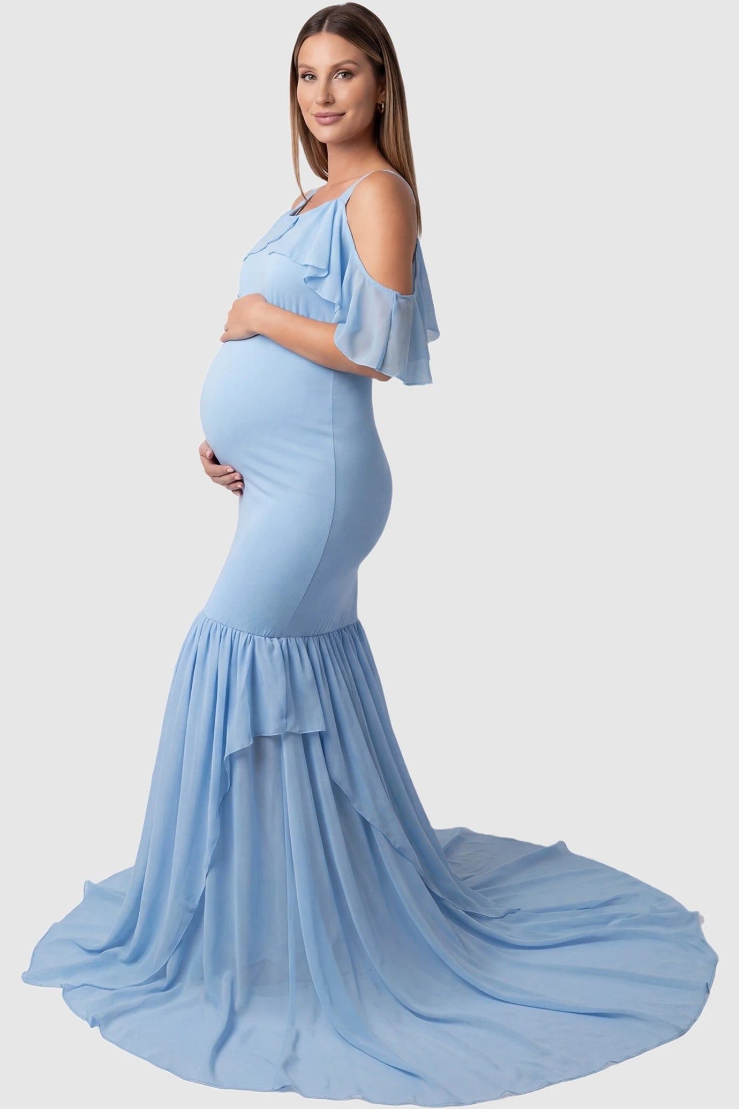 Off-shoulder flutter sleeve mermaid trailing maxi maternity dress in light blue featuring flowing double-layered skirt in side view on a pregnant model