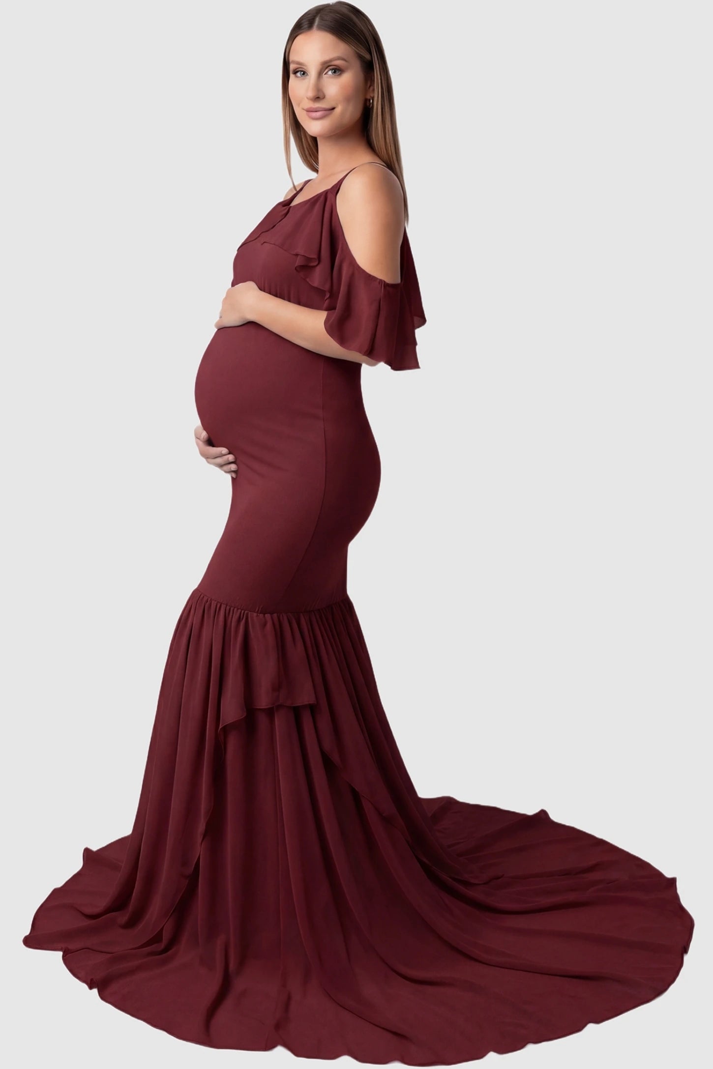 Off-Shoulder Flutter Sleeve Mermaid Trailing Maxi Maternity Dress Off-shoulder flutter sleeve mermaid trailing maxi maternity dress in wine red featuring flowing double-layered skirt in side view on a pregnant model