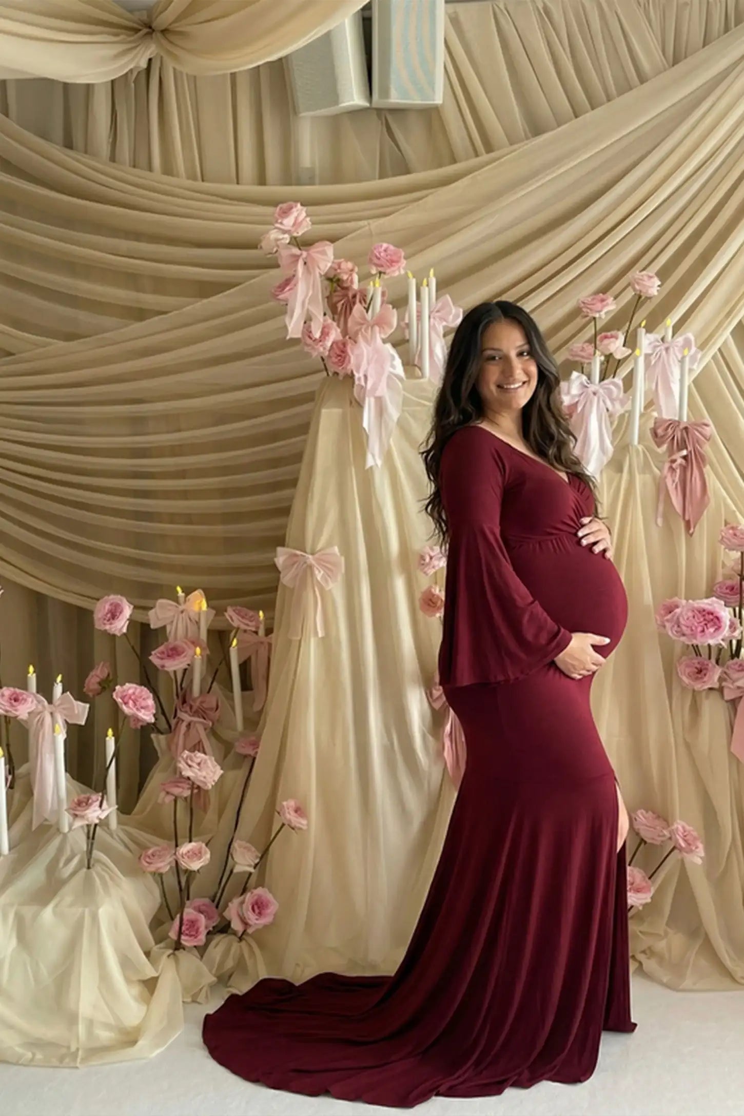 Mesh Flared Fishtail Maternity Gown Burgundy Mesh Flared Fishtail Maternity Gown featuring a V-neckline and bell sleeves on a pregnant model in a front view.