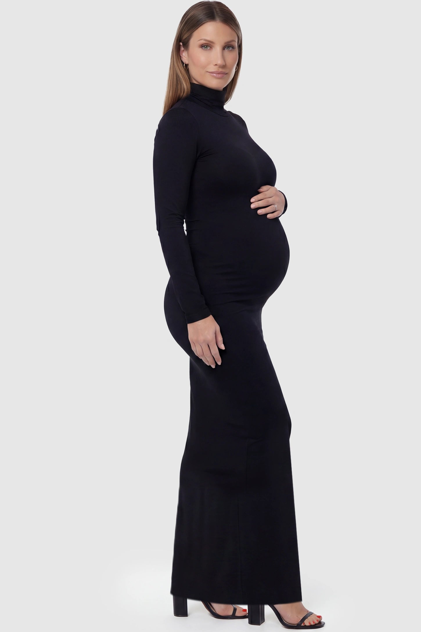Fitted Long Sleeve Mock Neck Maxi Maternity Dress Fitted long sleeve mock neck maxi maternity dress in black with mock neckline, side view on pregnant model