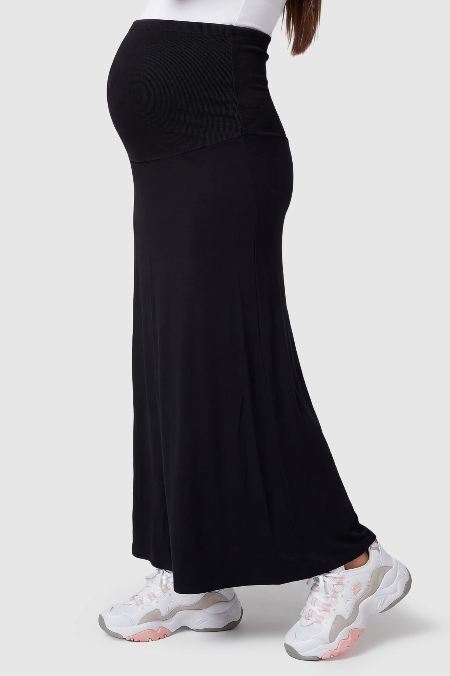 Modal High Waist A-Line Maternity Maxi Skirt Modal High Waist A-Line Maternity Maxi Skirt in Black featuring a stretchy high-waist on a pregnant model, side view.