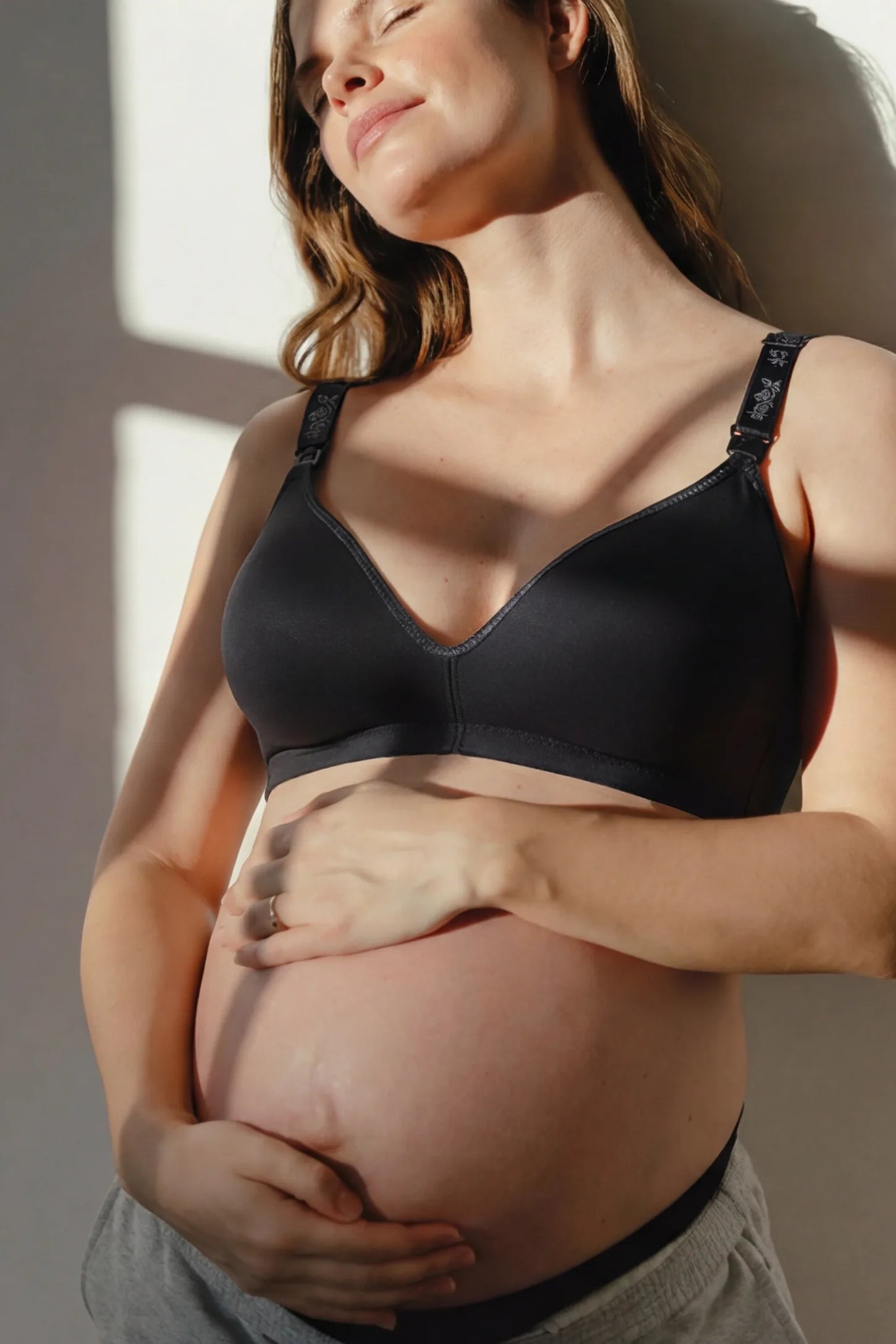 Wireless Medium Molded Cup Open-Clasp Nursing Bra Wireless medium molded cup open-clasp nursing bra in black with soft stretch fit, full body on editorial lifestyle model