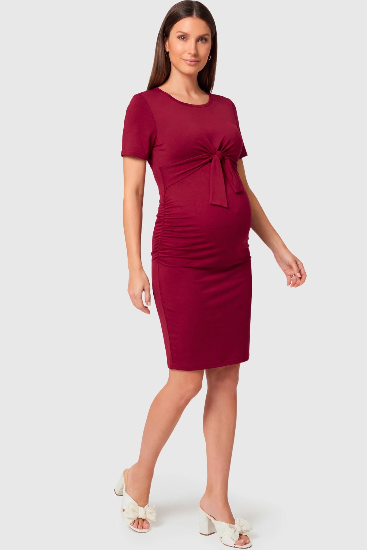 Crew Neck Bodycon Maternity & Nursing Midi Dress in wine red featuring twist-front detail and short sleeves on a pregnant model.