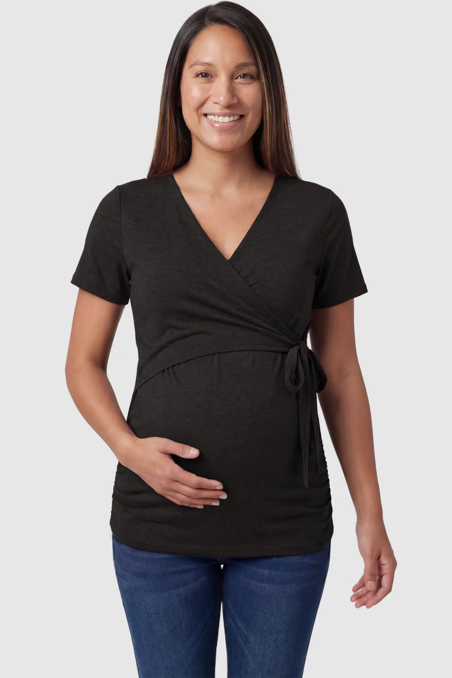 Nursing access V-neck wrap maternity and nursing top in black with wrap front and tie detail, front view on pregnant model