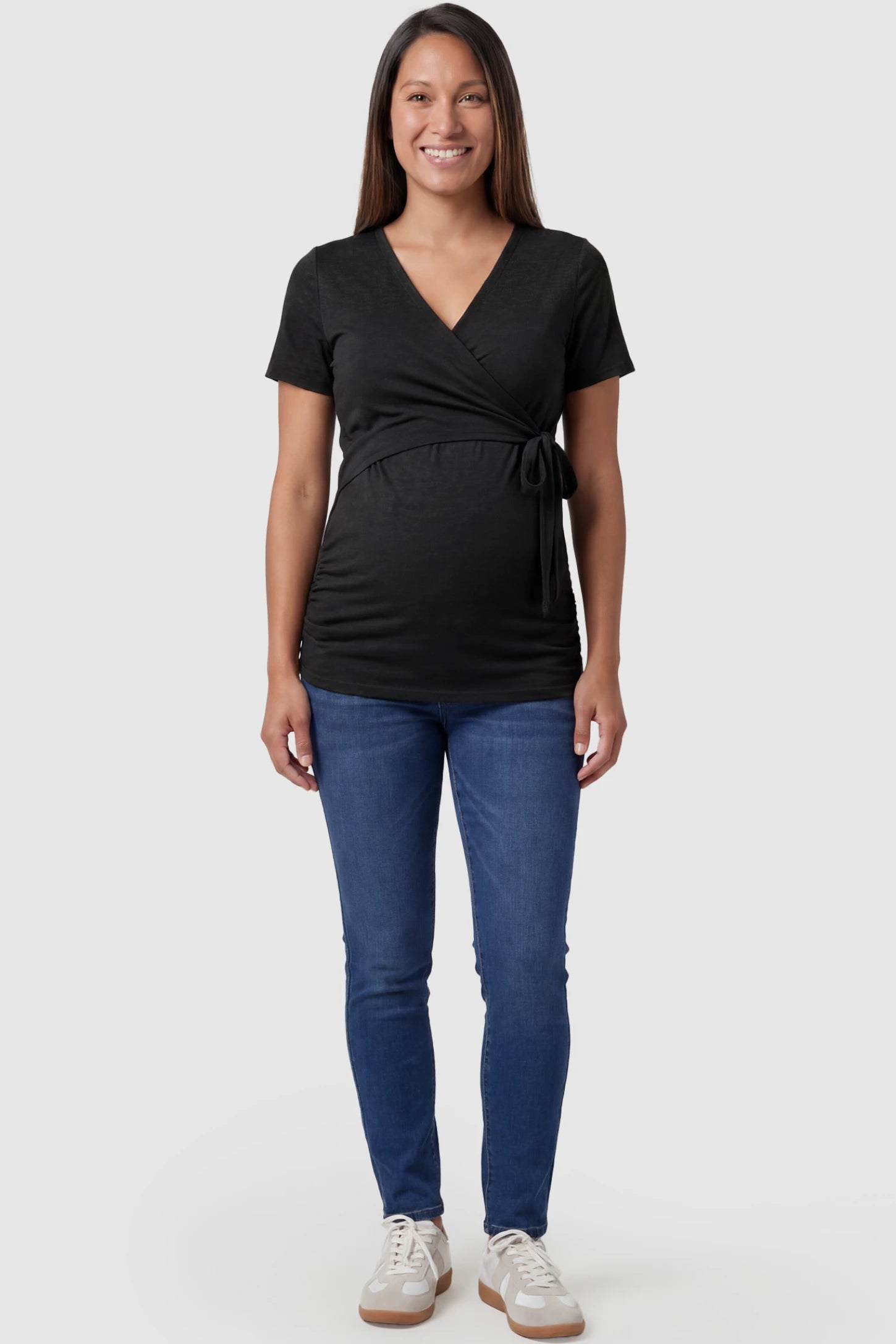 Nursing Access V-Neck Wrap Maternity & Nursing Top Nursing access V-neck wrap maternity and nursing top in black with wrap front and tie detail, front view on pregnant model