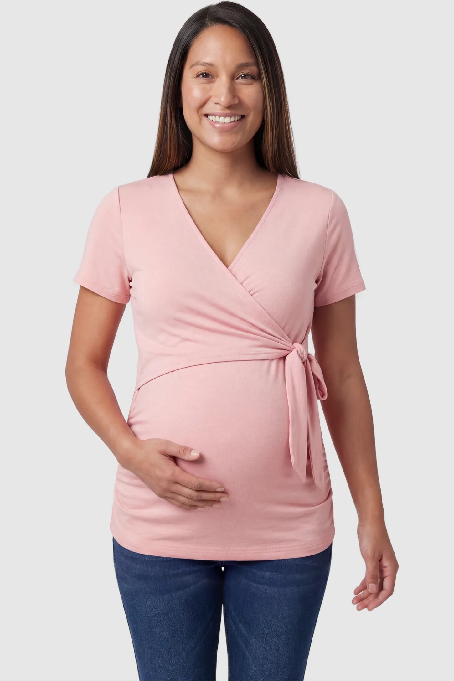 Nursing Access V-Neck Wrap Maternity & Nursing Top Nursing access V-neck wrap maternity and nursing top in pink with wrap front and tie detail, front view on pregnant model