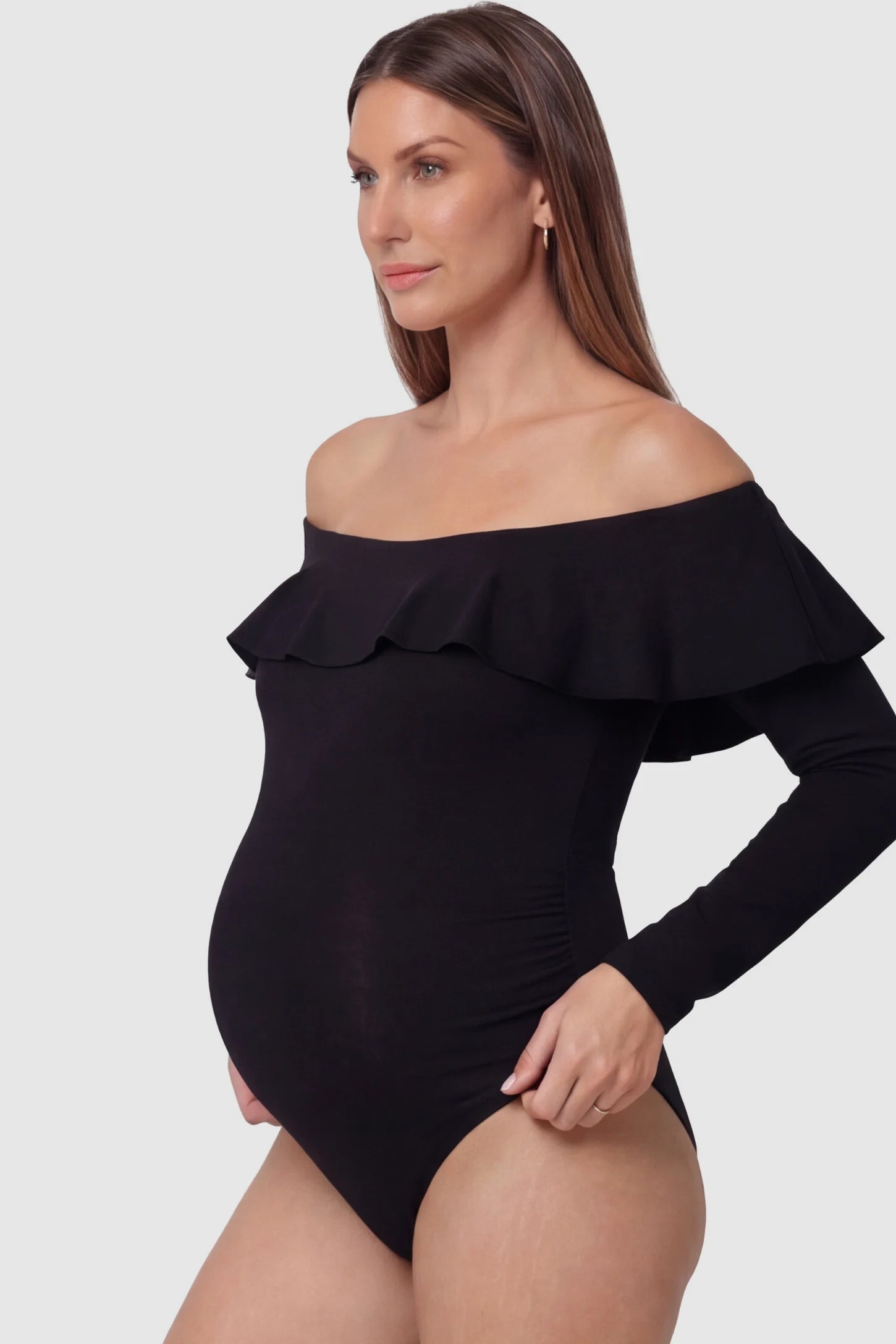 Ruffled Off-Shoulder Bodycon Fit Maternity Photography Bodysuit Ruffled Off-Shoulder Bodycon Fit Maternity Photography Bodysuit in black featuring dramatic ruffled neckline and long sleeves on a pregnant model
