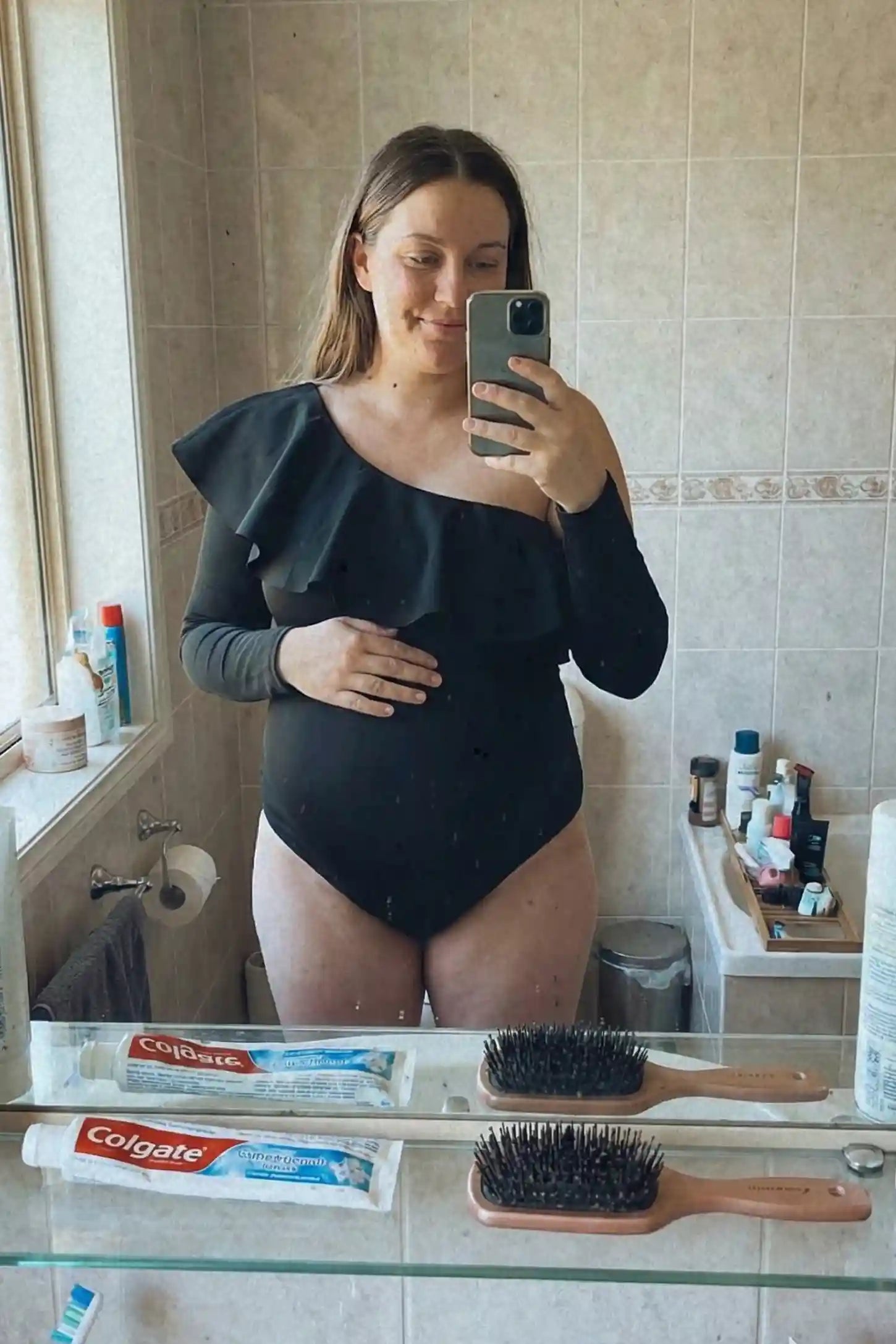 Ruffled Off-Shoulder Bodycon Fit Maternity Photography Bodysuit Ruffled Off-Shoulder Bodycon Fit Maternity Photography Bodysuit in black featuring dramatic ruffled neckline and long sleeves on a pregnant model