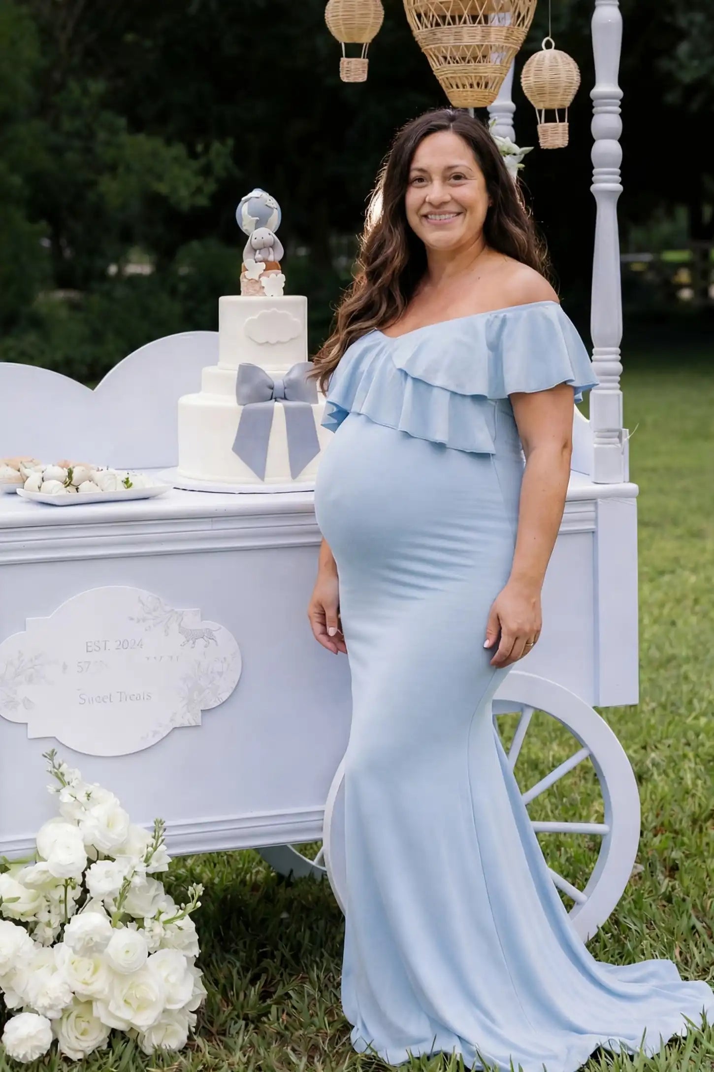 Ruffle Off-Shoulder Slim Fit Maxi Maternity Dress Ruffle off-shoulder slim fit maxi maternity dress in light blue with flowing maxi length, on an editorial lifestyle model