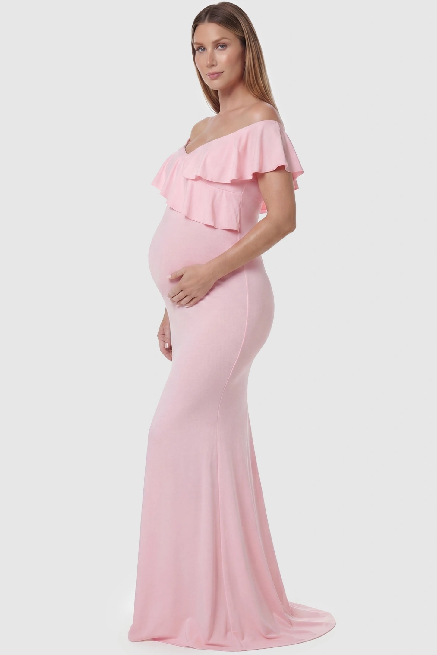 Ruffle Off-Shoulder Slim Fit Maxi Maternity Dress Ruffle off-shoulder slim fit maxi maternity dress in pink featuring off-shoulder and elegant ruffle detailing fabric in side view on a pregnant model