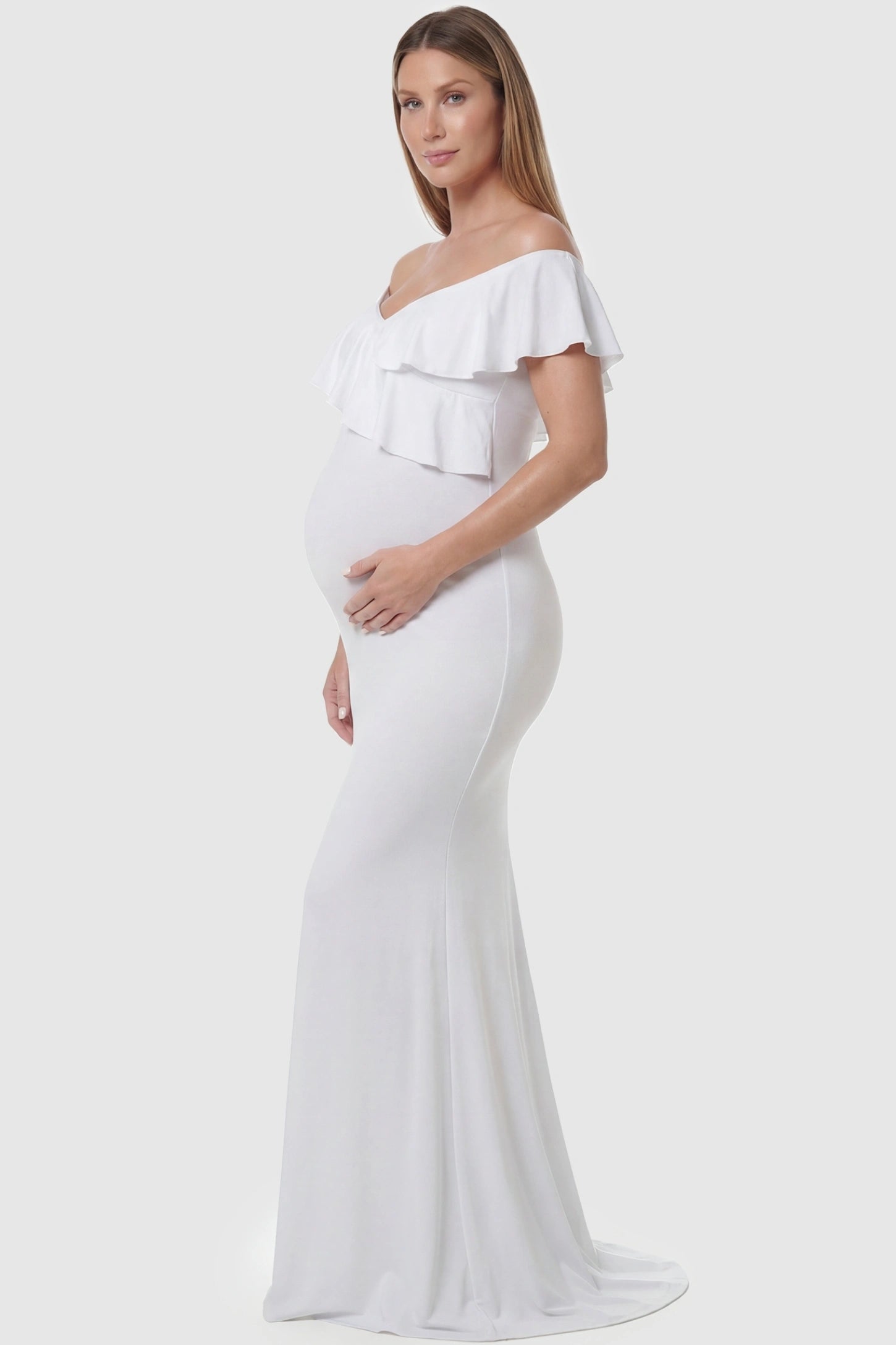 Ruffle off-shoulder slim fit maxi maternity dress in white featuring off-shoulder and elegant ruffle detailing fabric in side view on a pregnant model