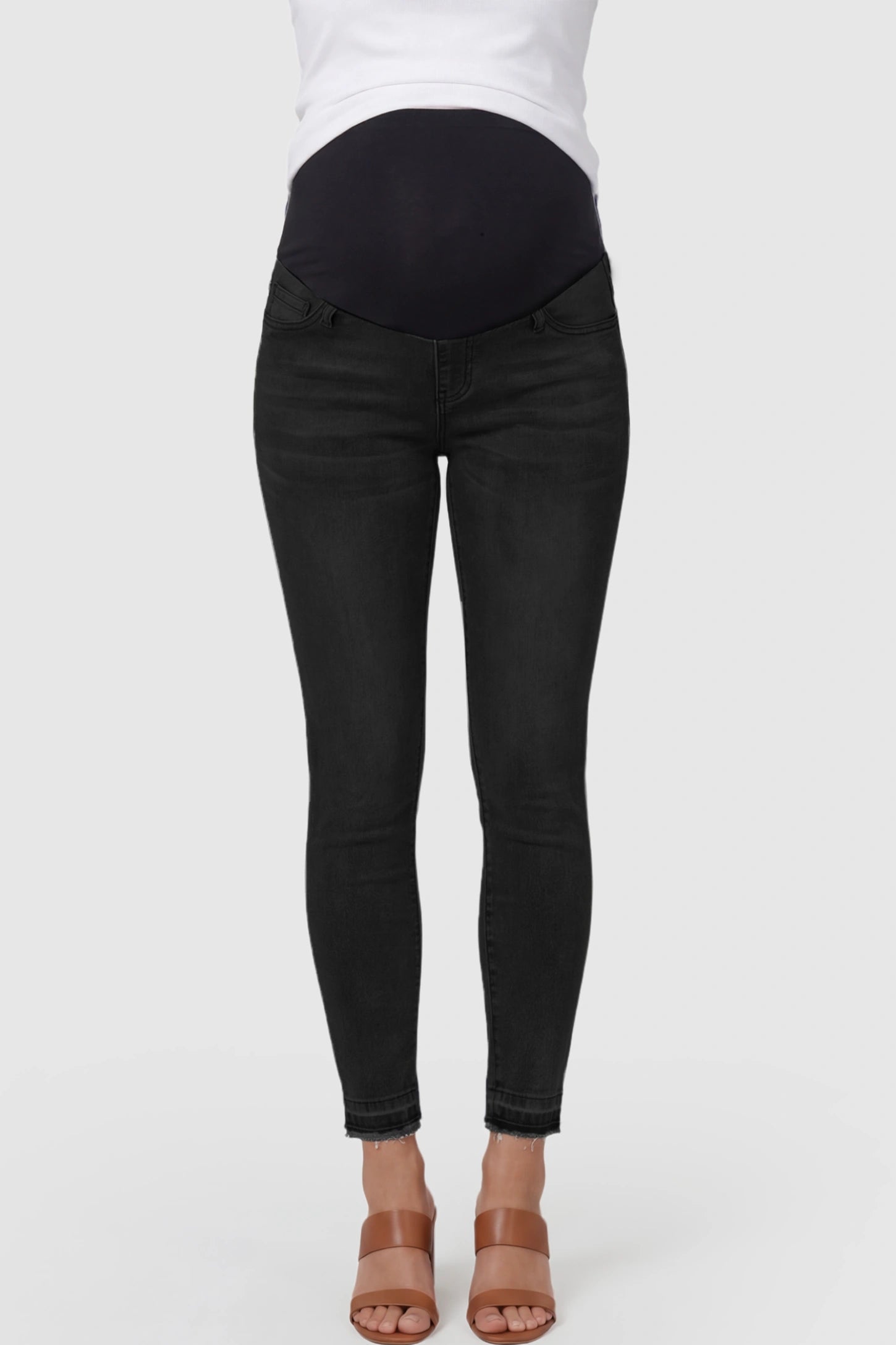 Full Panel Released Hem Maternity Skinny Jeans Full Panel Released Hem Maternity Skinny Jeans in Black featuring a released hem and over-the-belly panel on a pregnant model showing front.