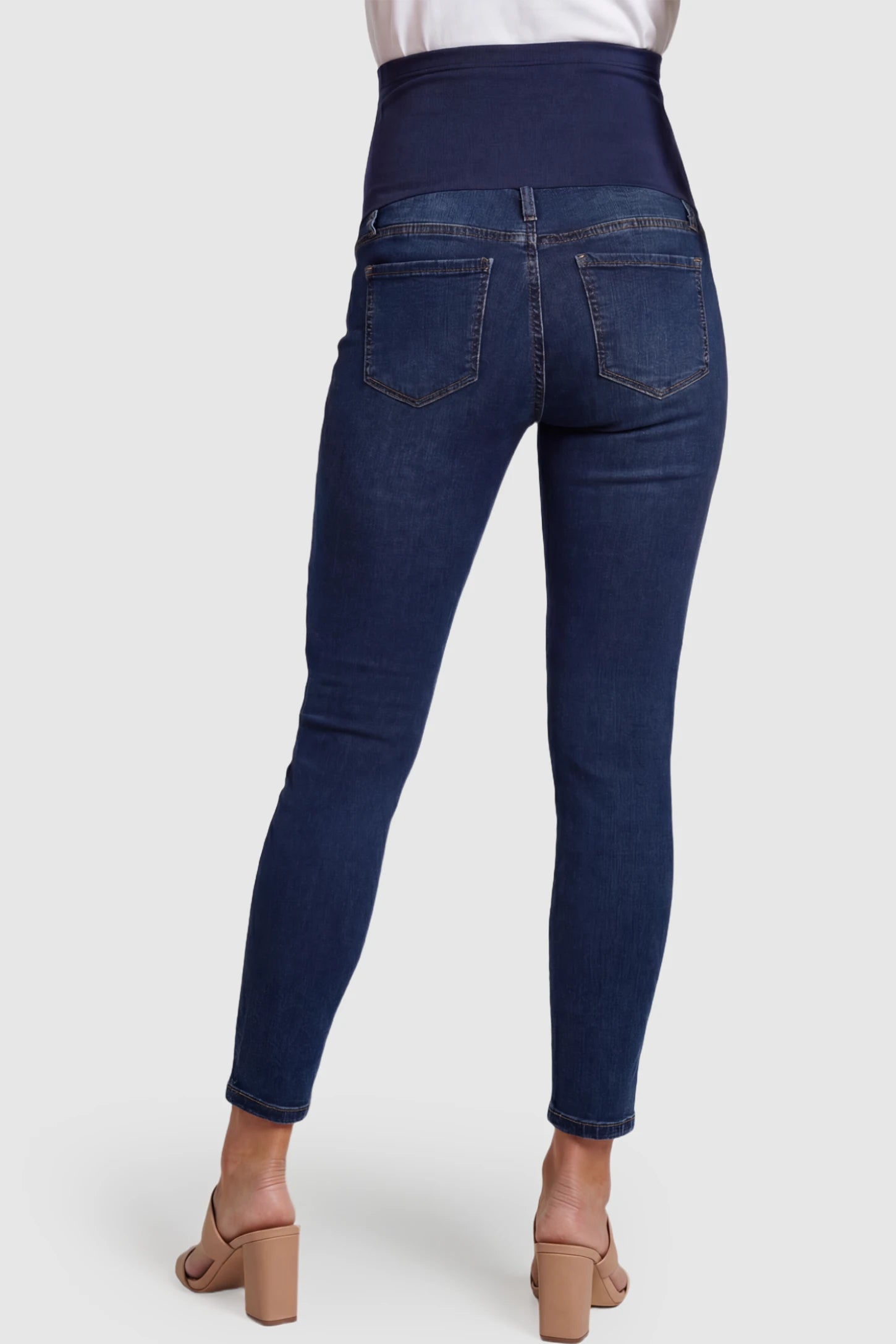 Full Panel Released Hem Maternity Skinny Jeans Full Panel Released Hem Maternity Skinny Jeans in Dark Blue featuring a released hem and over-the-belly panel on a pregnant model showing back.