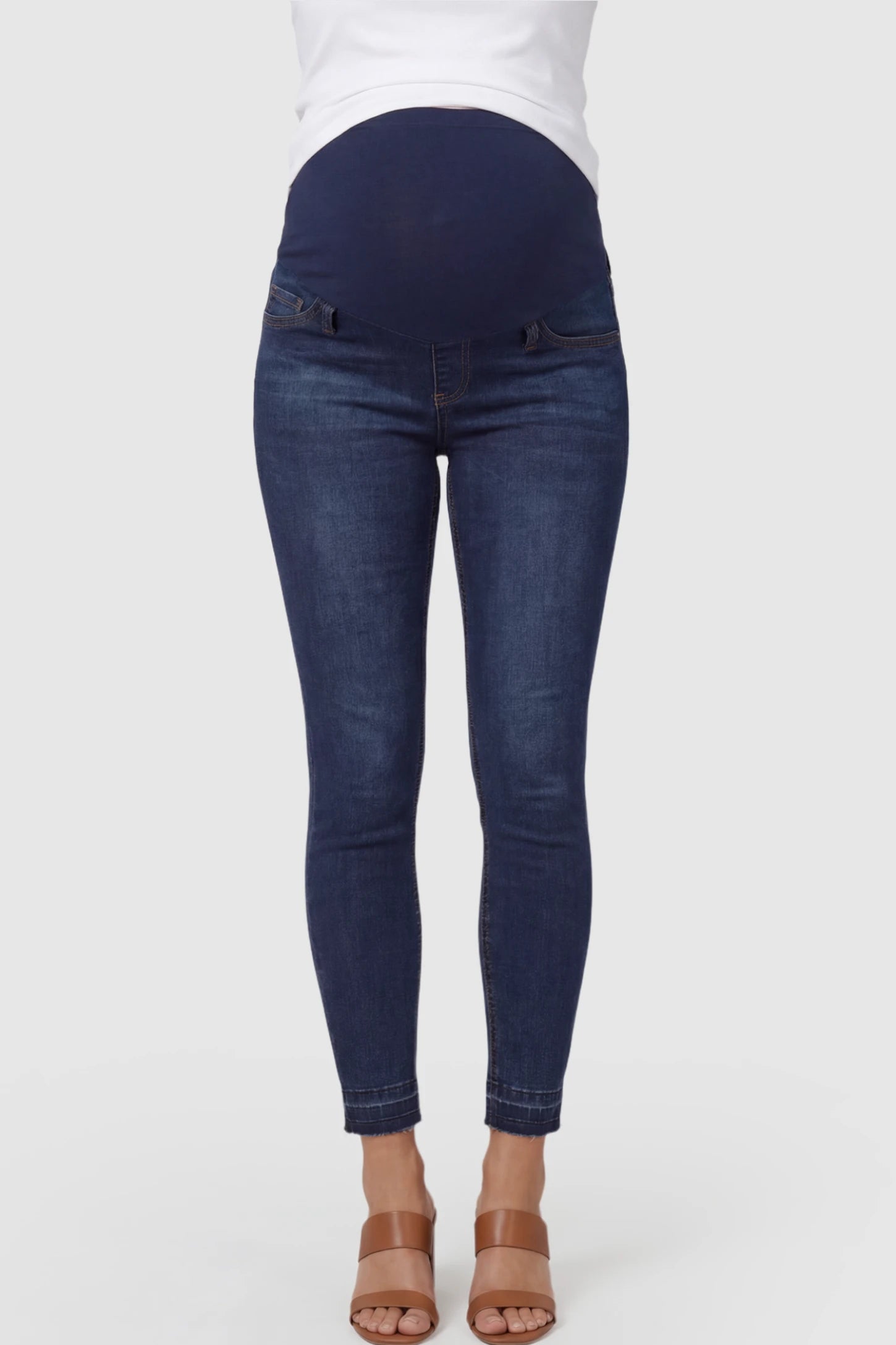 Full Panel Released Hem Maternity Skinny Jeans Full Panel Released Hem Maternity Skinny Jeans in Dark Blue featuring a released hem and over-the-belly panel on a pregnant model showing front.