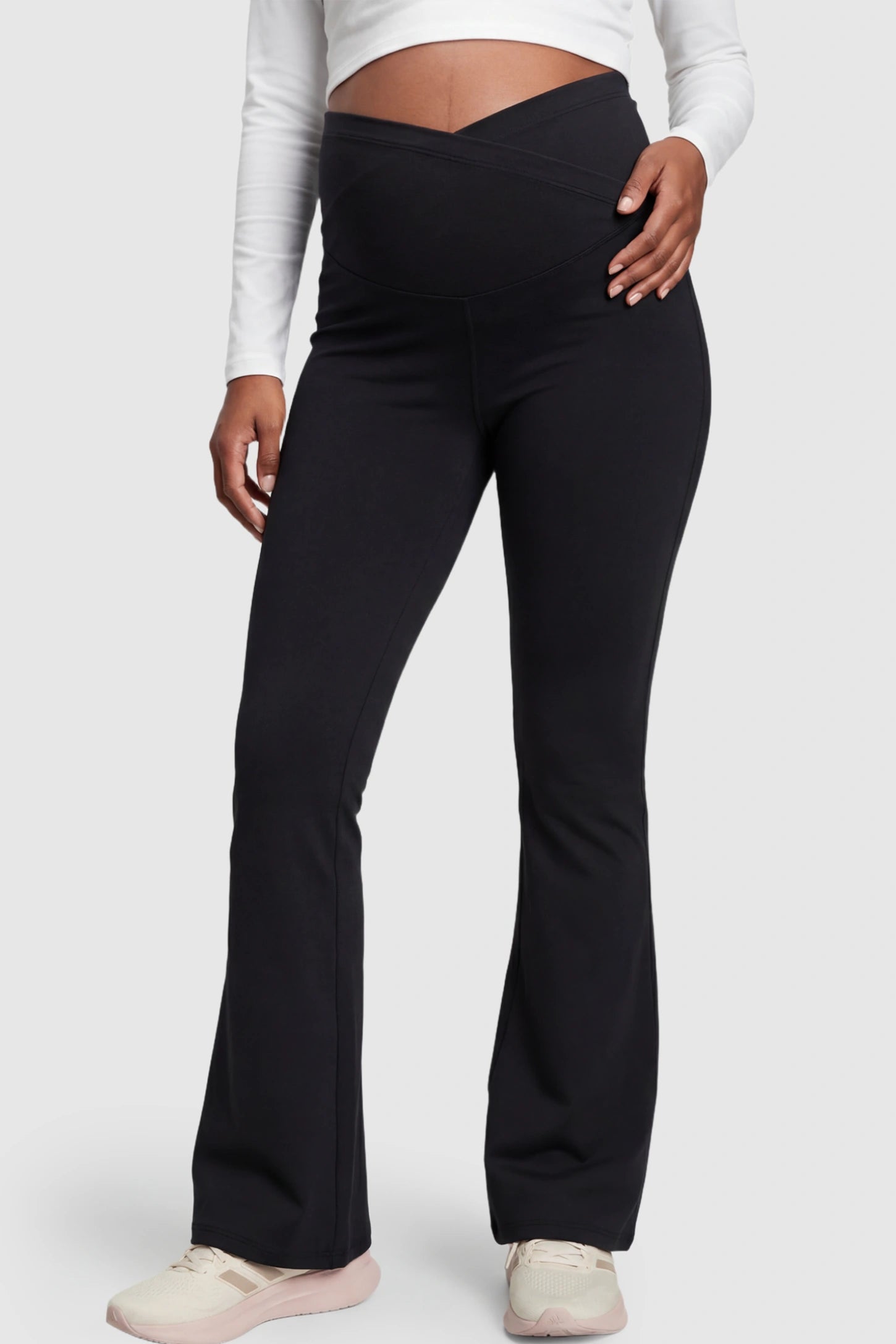 Crossover Waistline Flared Maternity Pants in Black featuring a V-shaped band on a pregnant model.