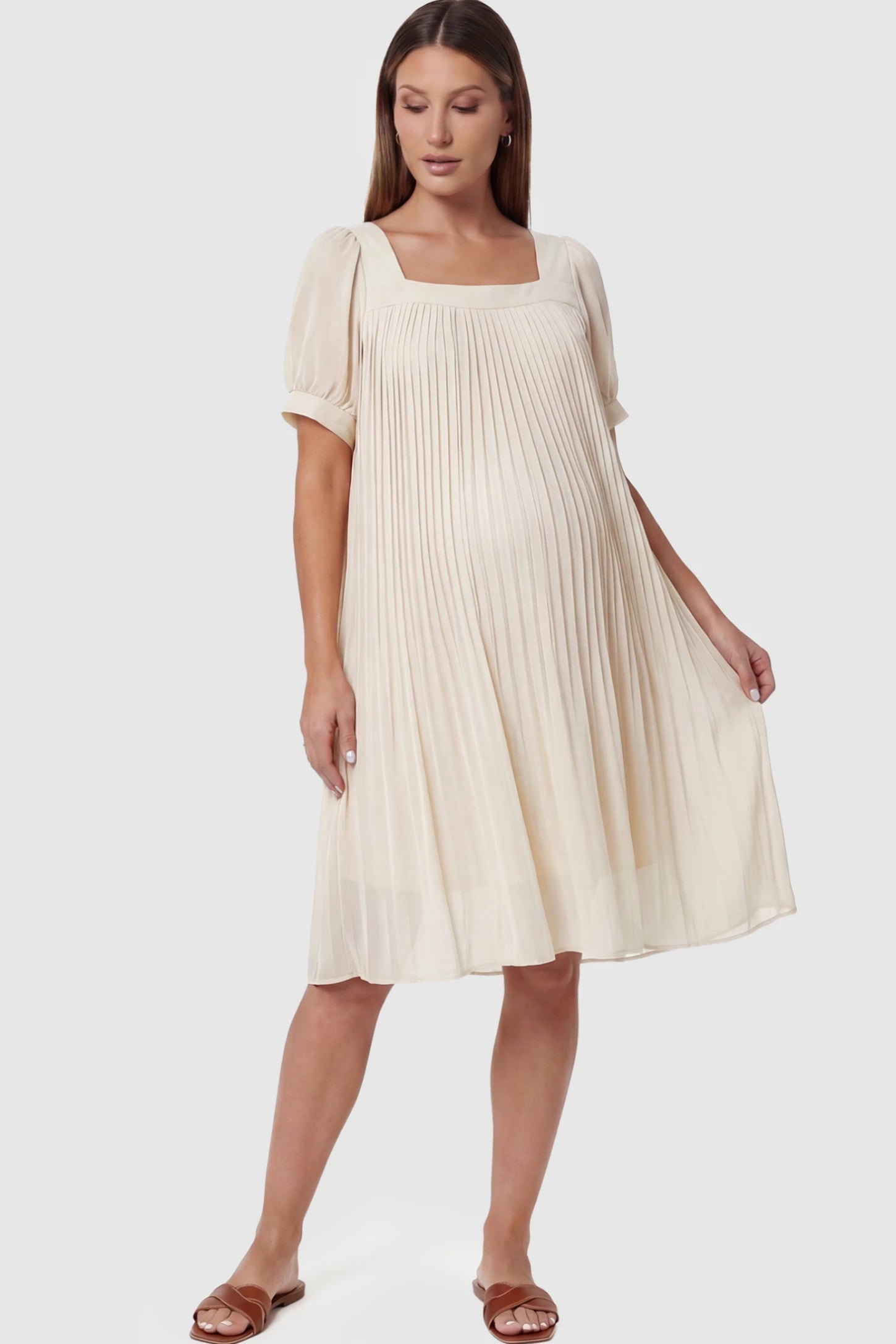 Pleated Front Square Neck Maternity Dress Pleated Front Square Neck Maternity Dress in Off White featuring accordion pleats and short sleeves on a pregnant model.